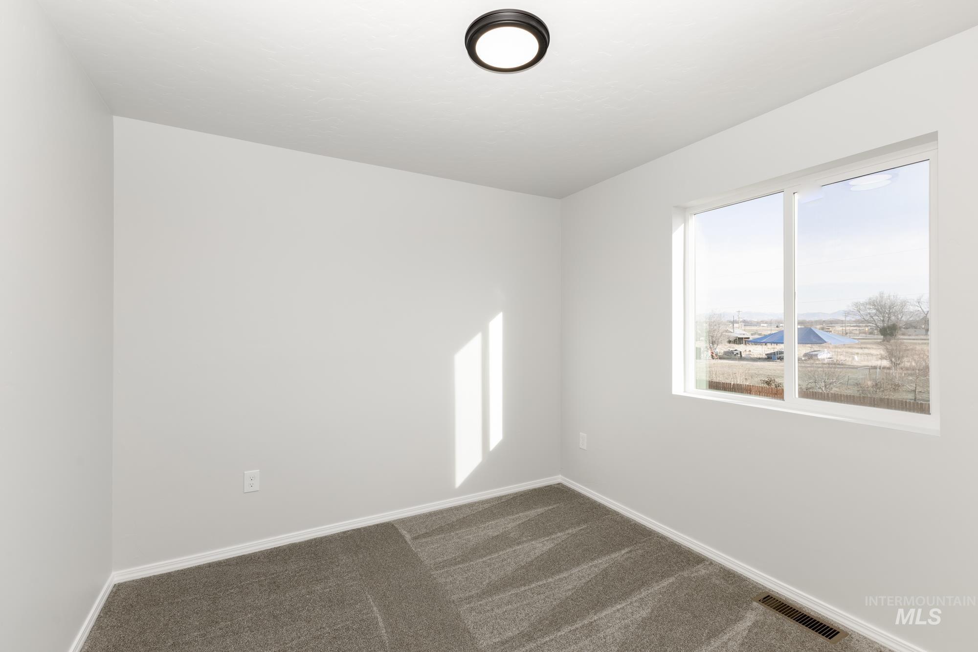 Spare room featuring dark colored carpet and plenty of natural light