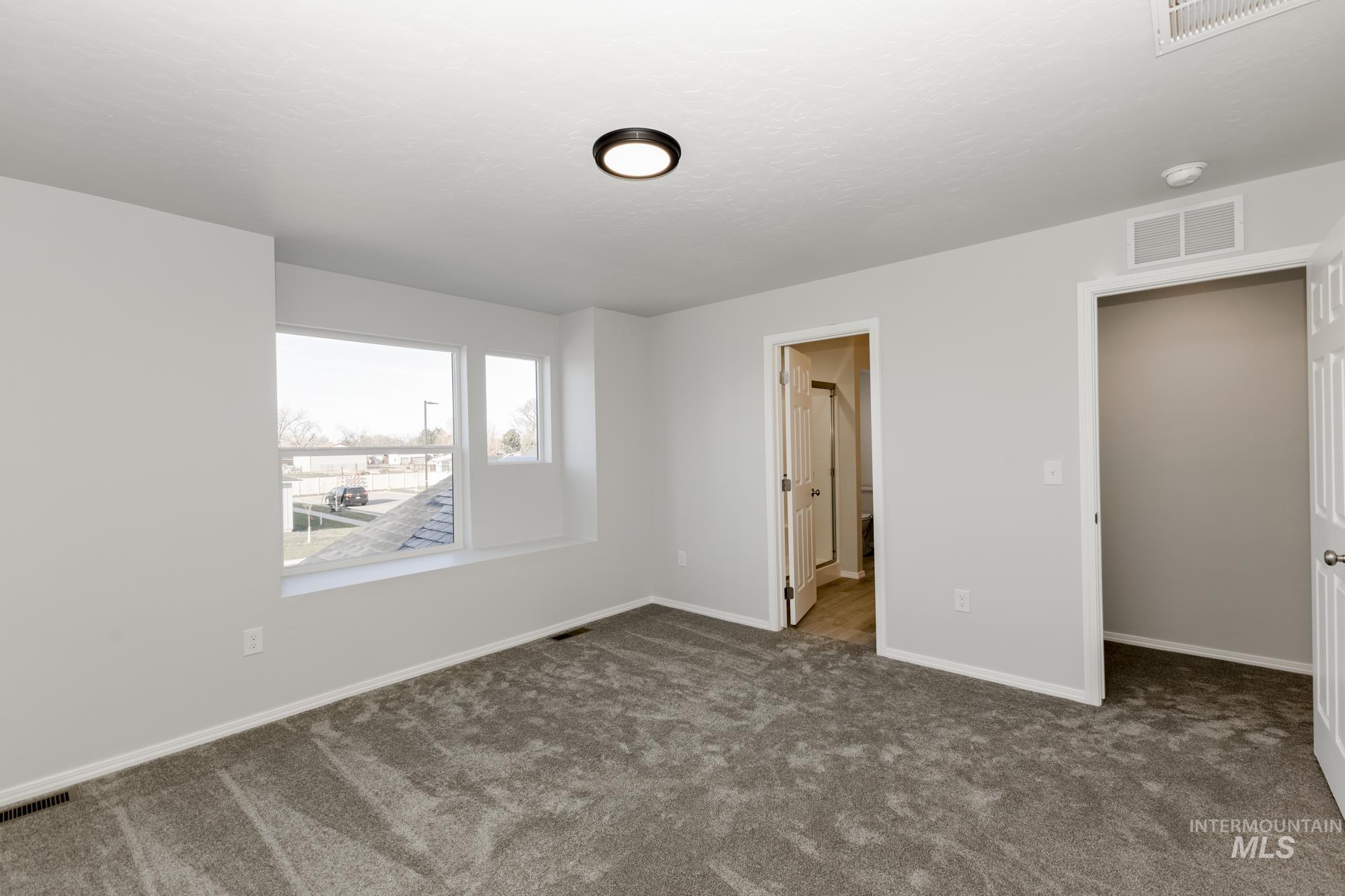 Unfurnished bedroom featuring dark carpet and connected bathroom