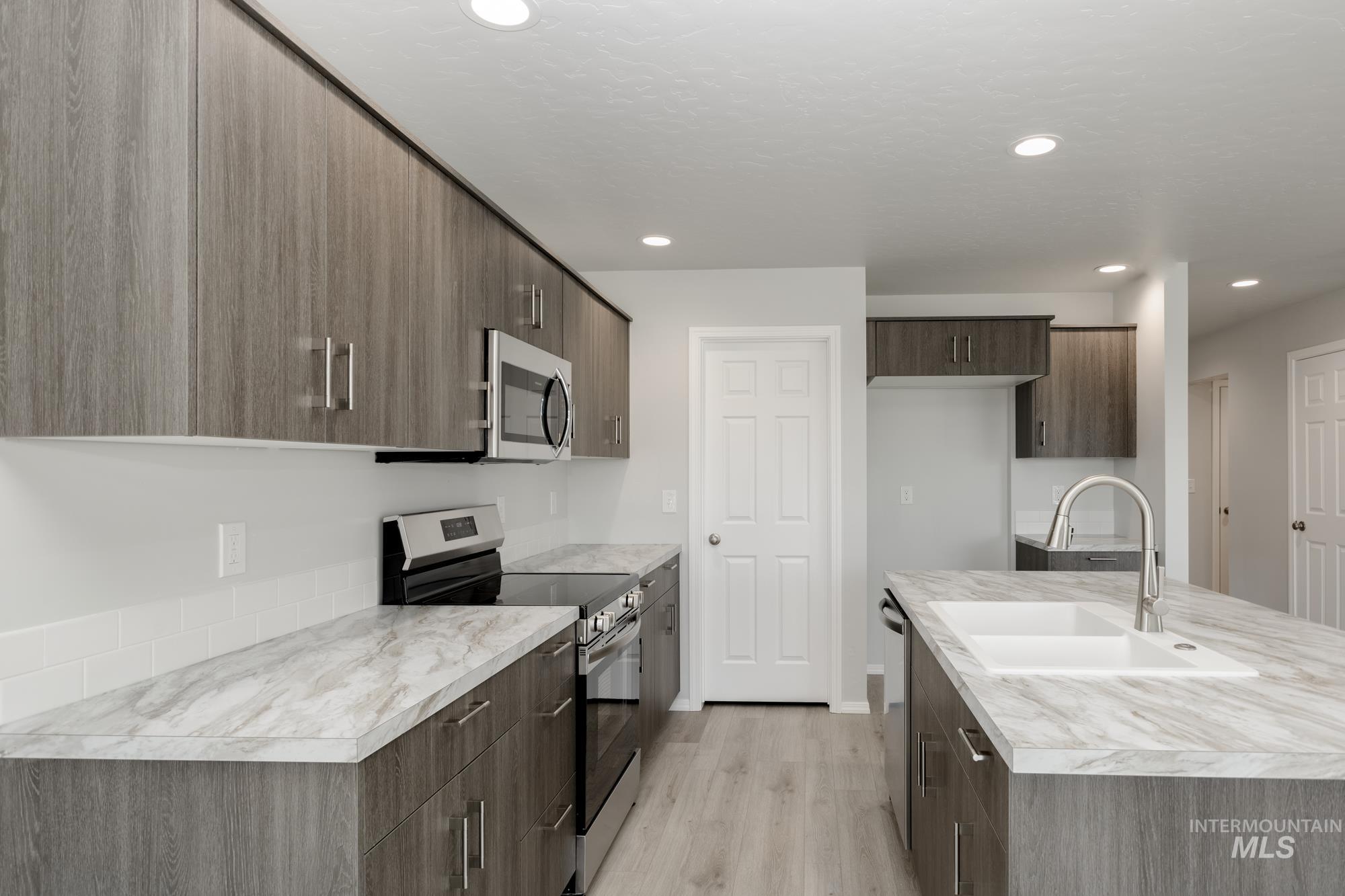 Kitchen with stainless steel appliances, light wood-style floors, light countertops, modern cabinets, and recessed lighting