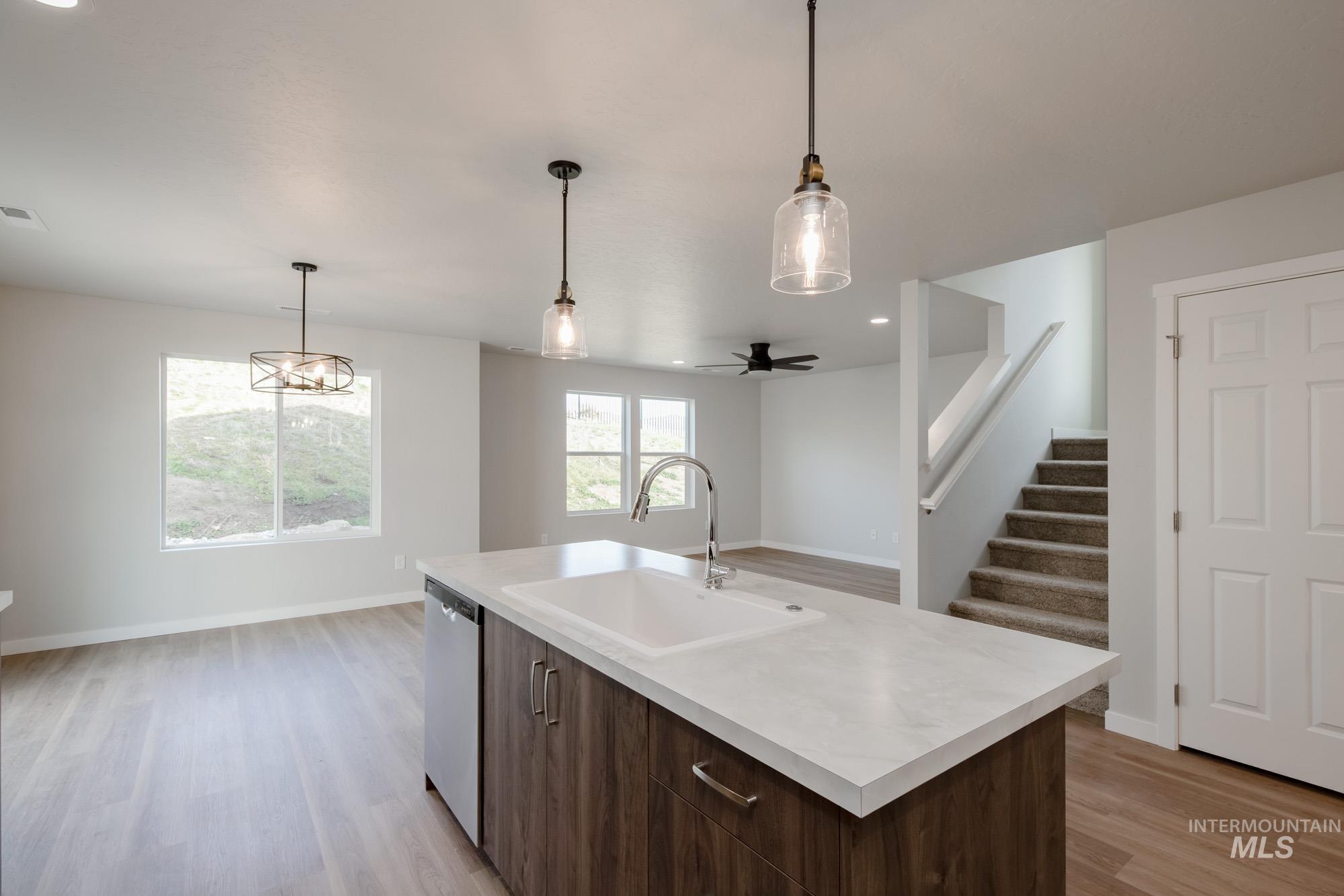 Kitchen with dark brown cabinets, light countertops, decorative light fixtures, open floor plan, and recessed lighting