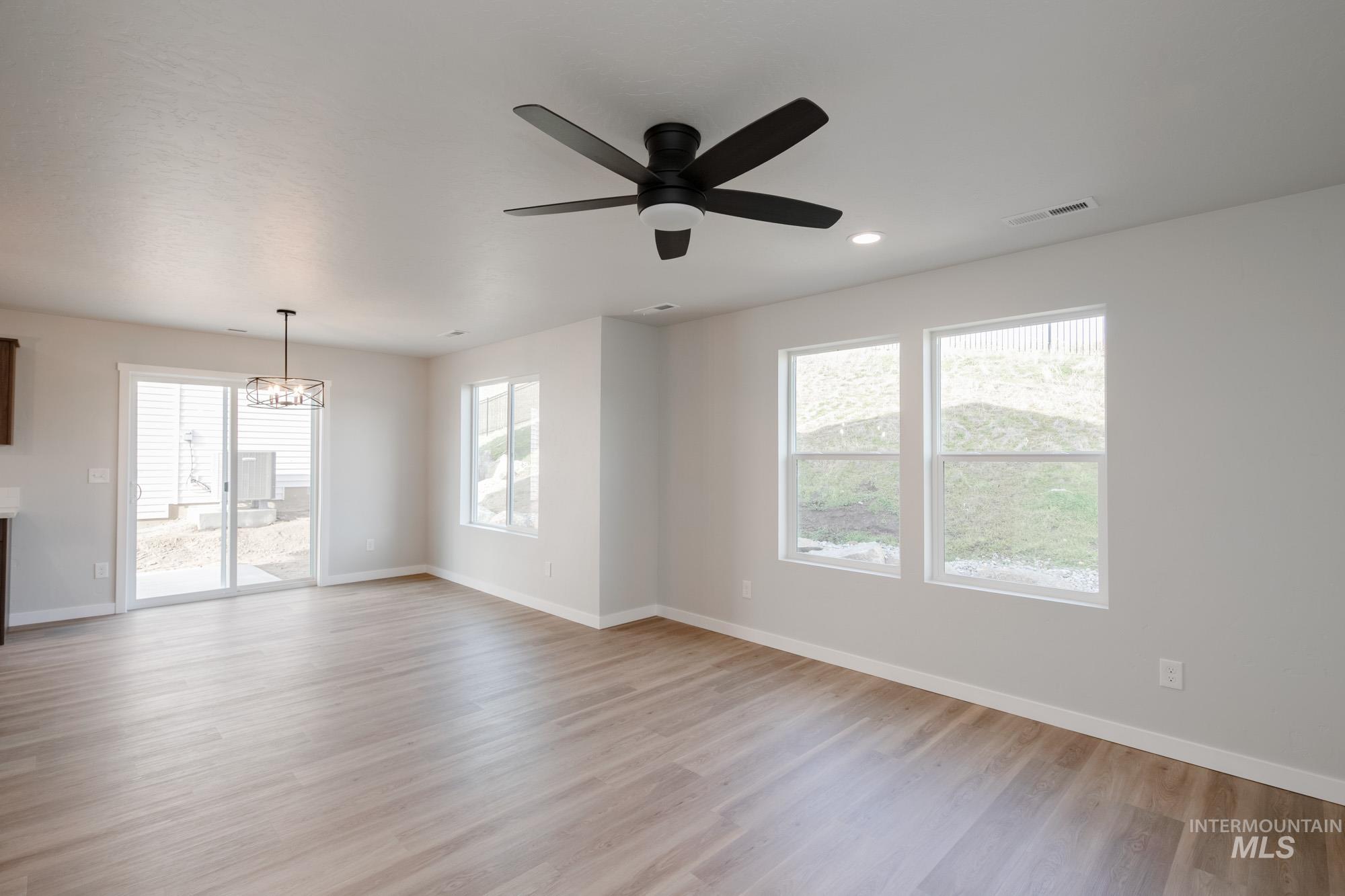 Empty room featuring light wood-style flooring, a chandelier, a ceiling fan, and recessed lighting