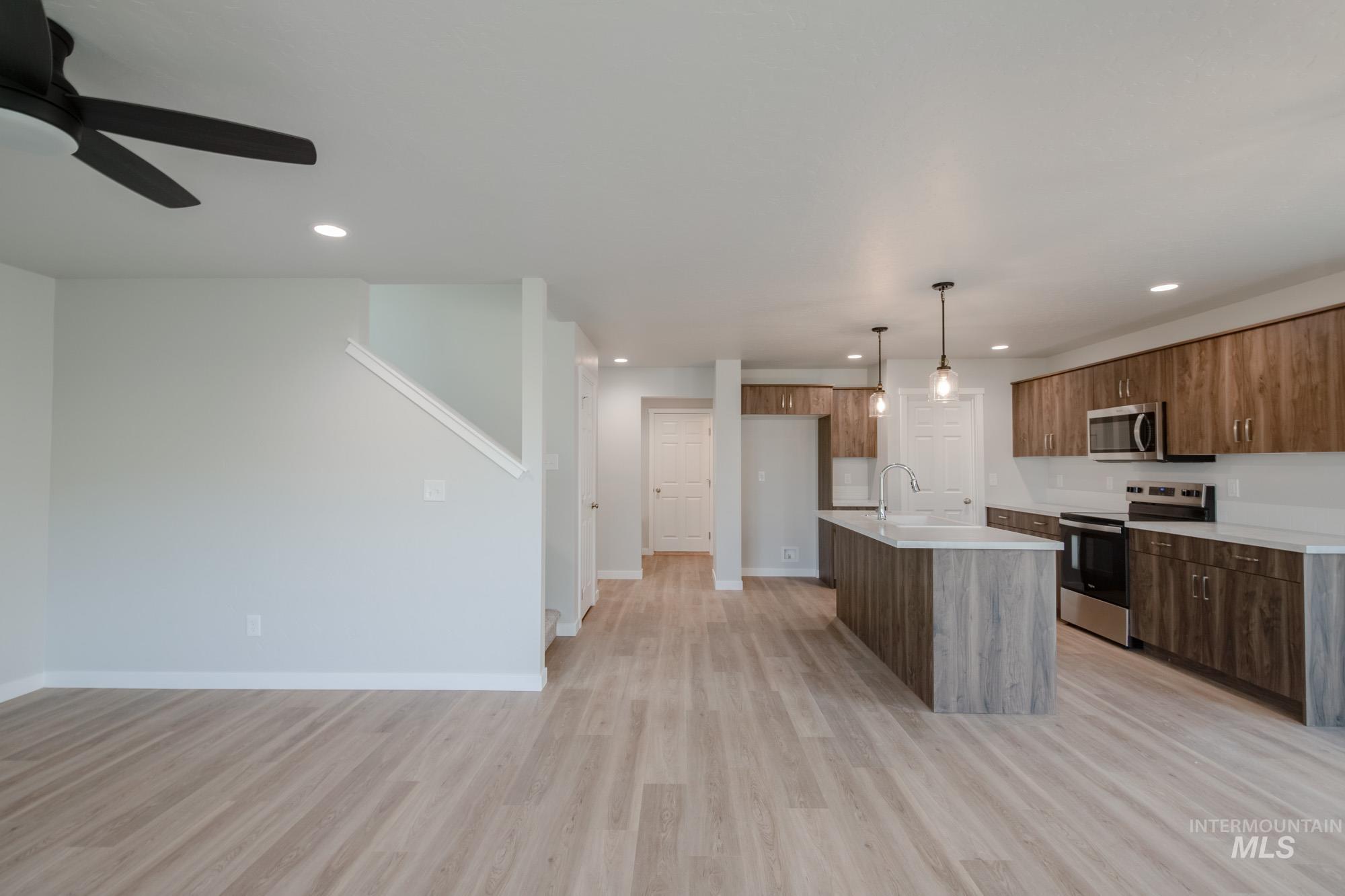 Kitchen featuring appliances with stainless steel finishes, a center island with sink, decorative light fixtures, recessed lighting, and light wood finished floors