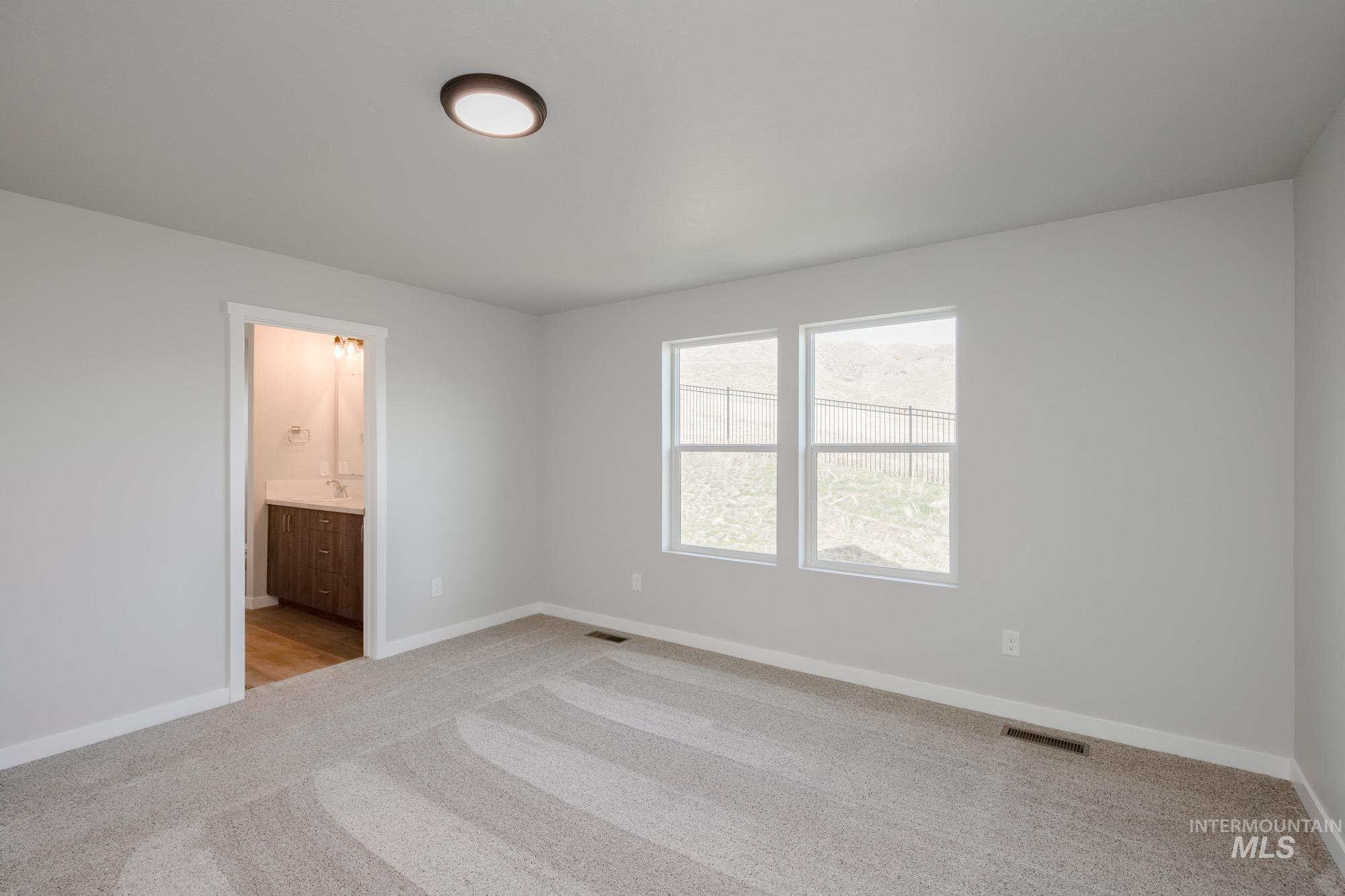 Unfurnished bedroom featuring light carpet and connected bathroom