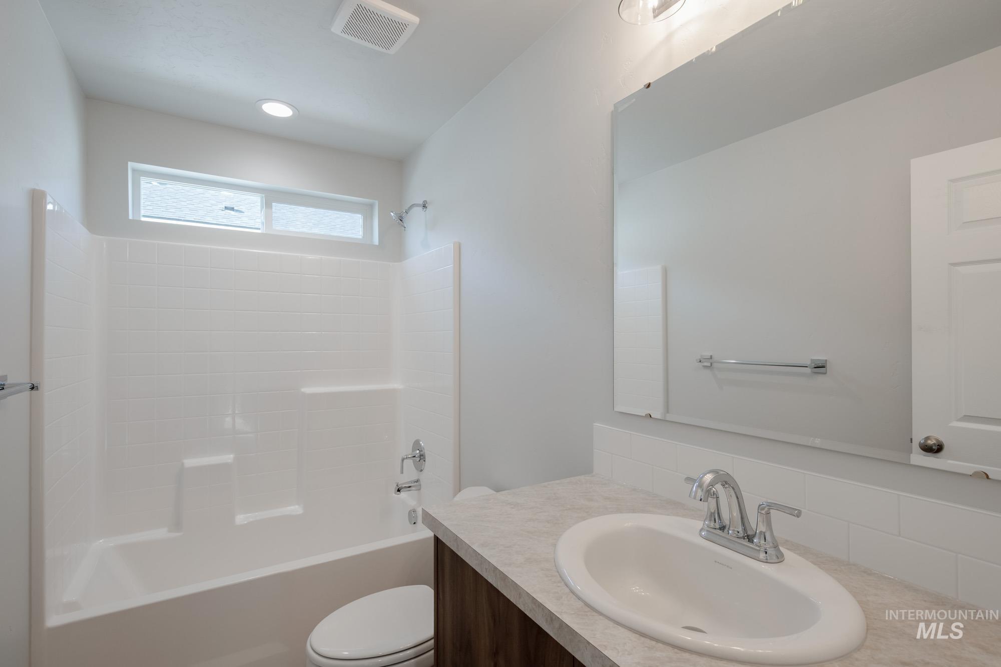 Full bathroom featuring shower / bathtub combination, vanity, and tasteful backsplash