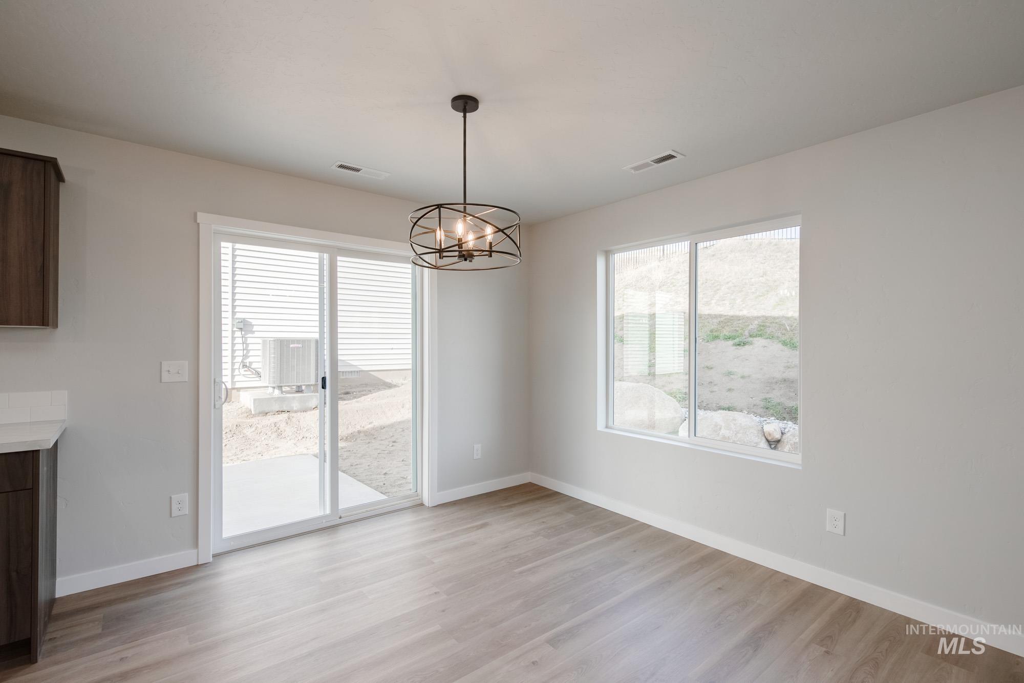 Unfurnished dining area featuring light wood-style floors, healthy amount of natural light, and a chandelier