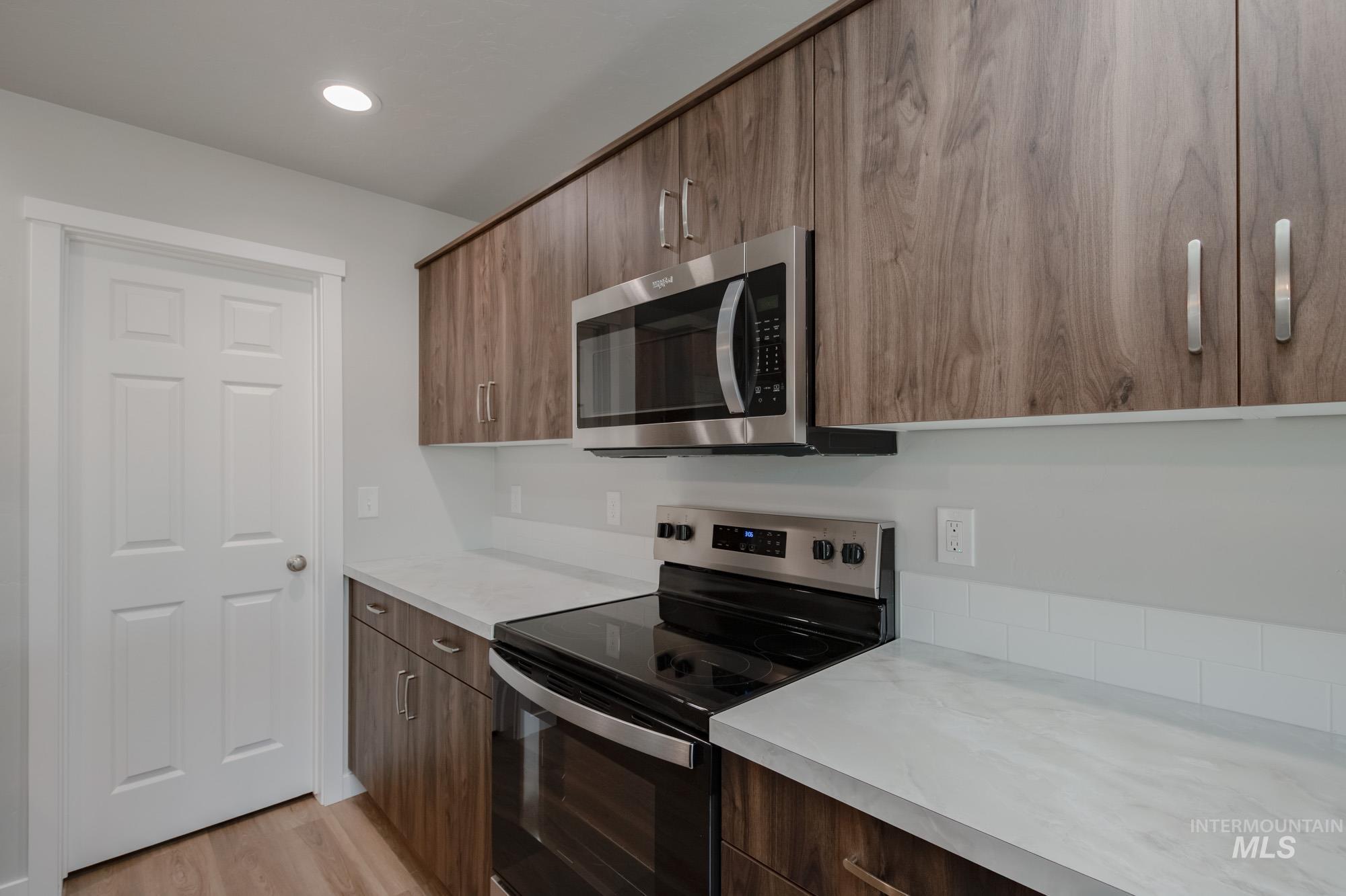 Kitchen with appliances with stainless steel finishes, light countertops, modern cabinets, and recessed lighting