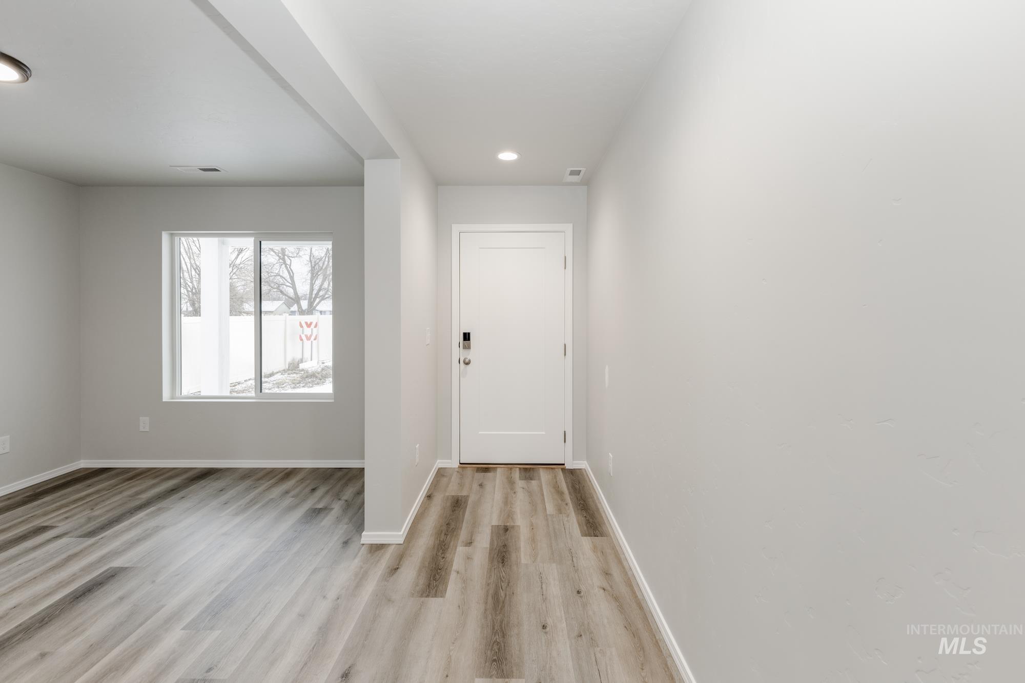 Foyer entrance with light wood finished floors and recessed lighting