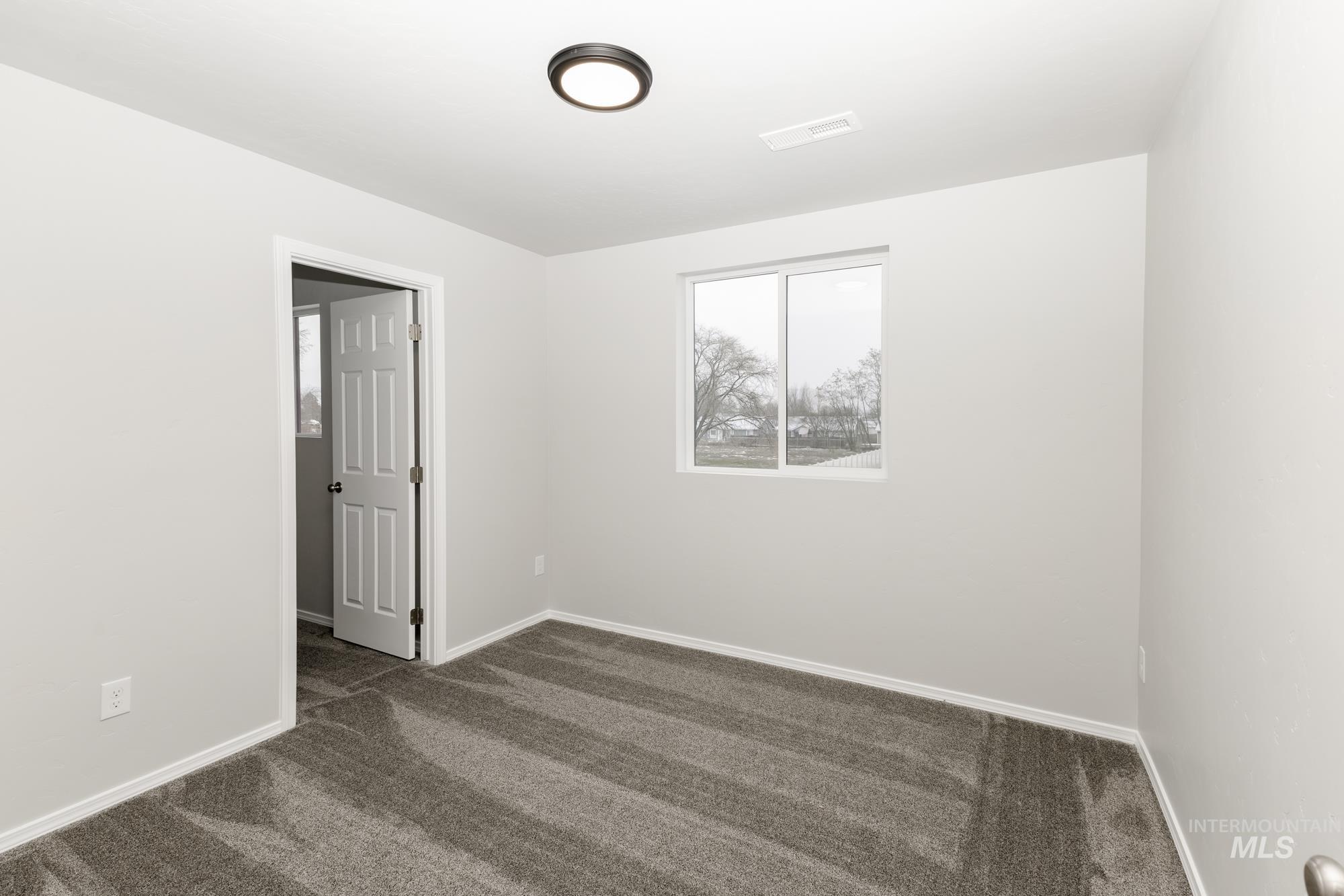 Unfurnished room featuring dark colored carpet and baseboards