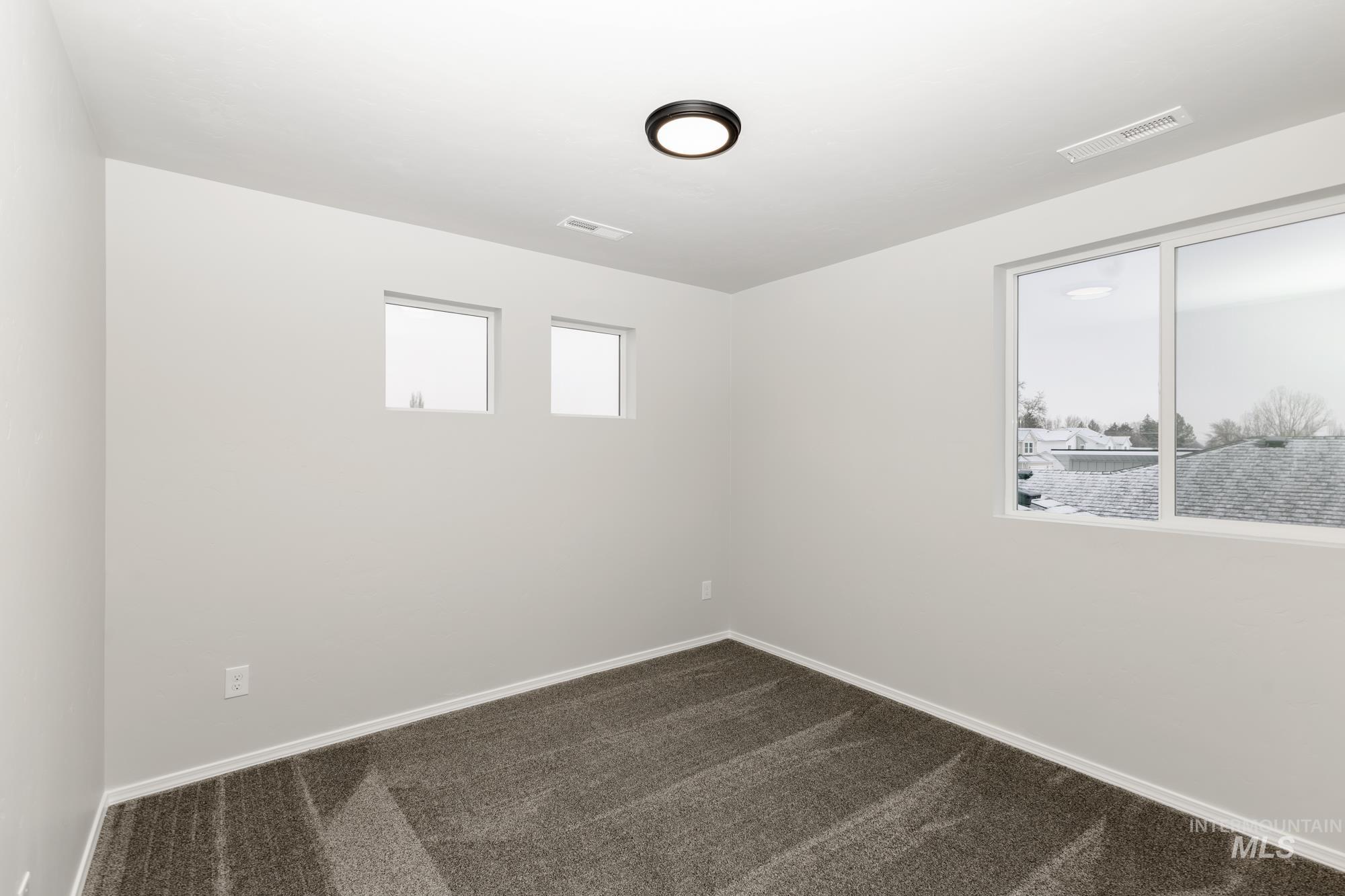 Spare room featuring dark carpet and baseboards