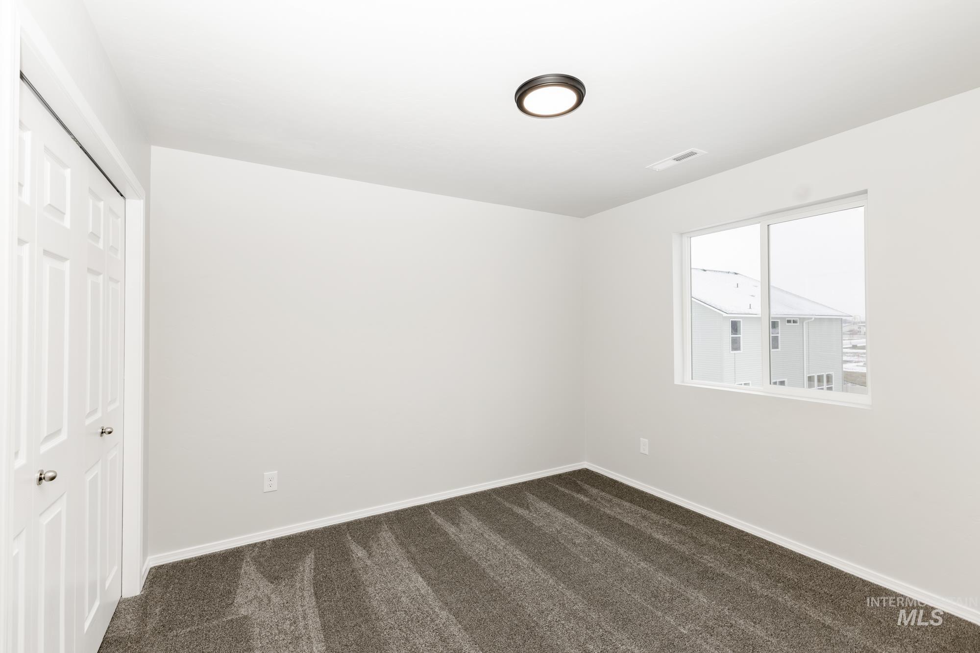 Unfurnished bedroom featuring dark carpet and a closet
