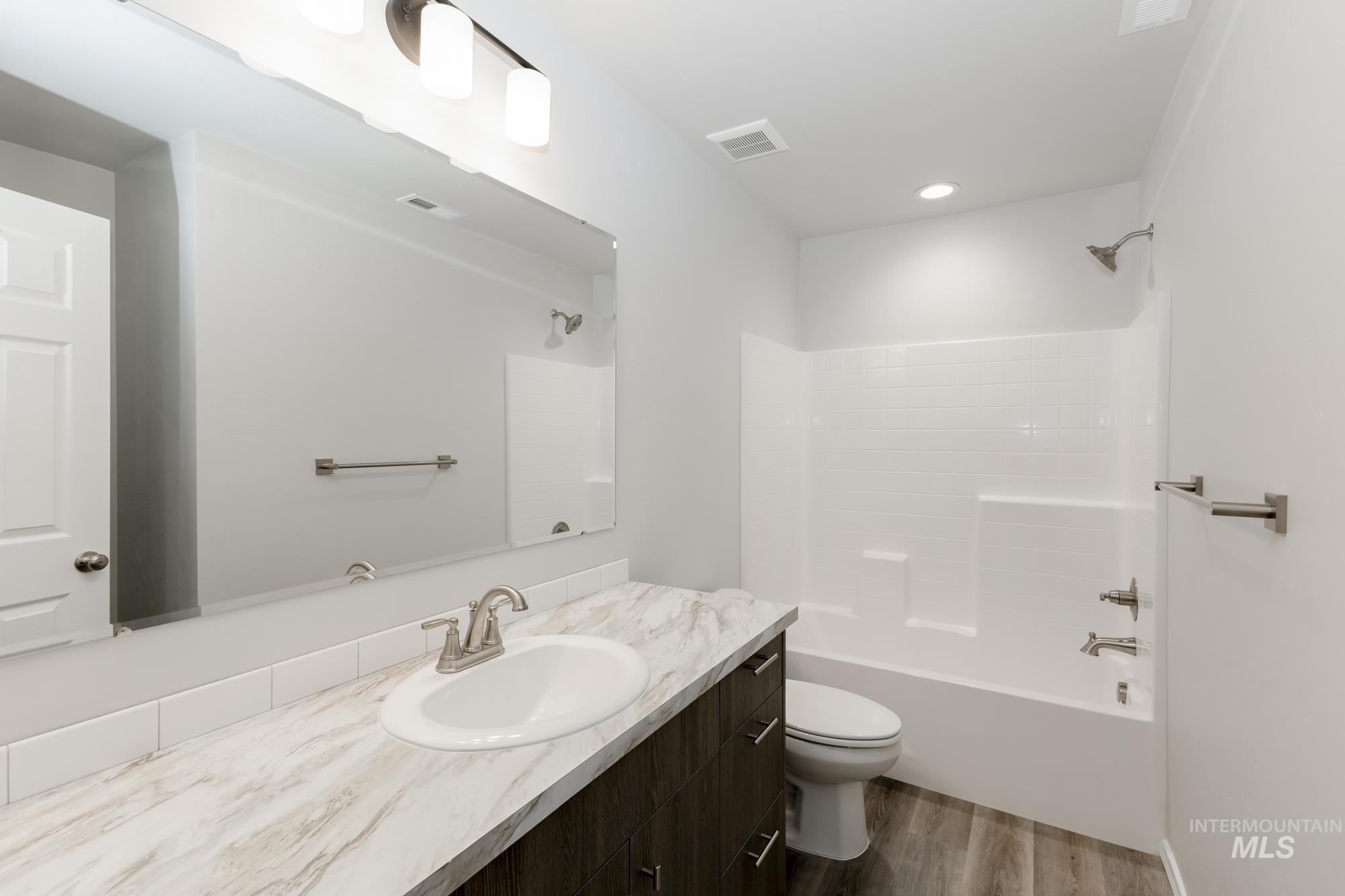 Bathroom featuring  shower combination, vanity, and dark wood-type flooring