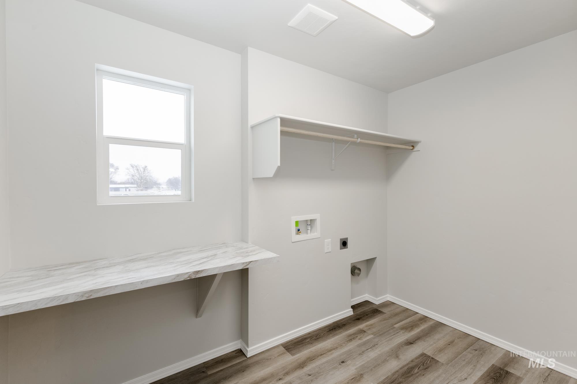 Laundry area featuring light wood finished floors, hookup for an electric dryer, and washer hookup