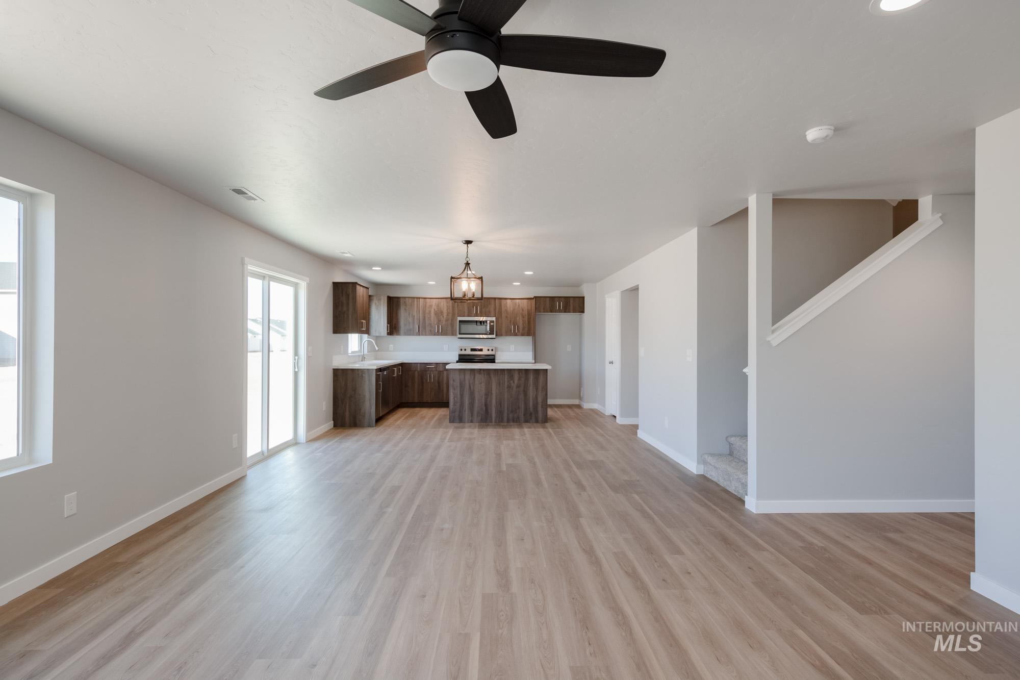 Unfurnished living room with light wood-style floors, a ceiling fan, recessed lighting, and stairs
