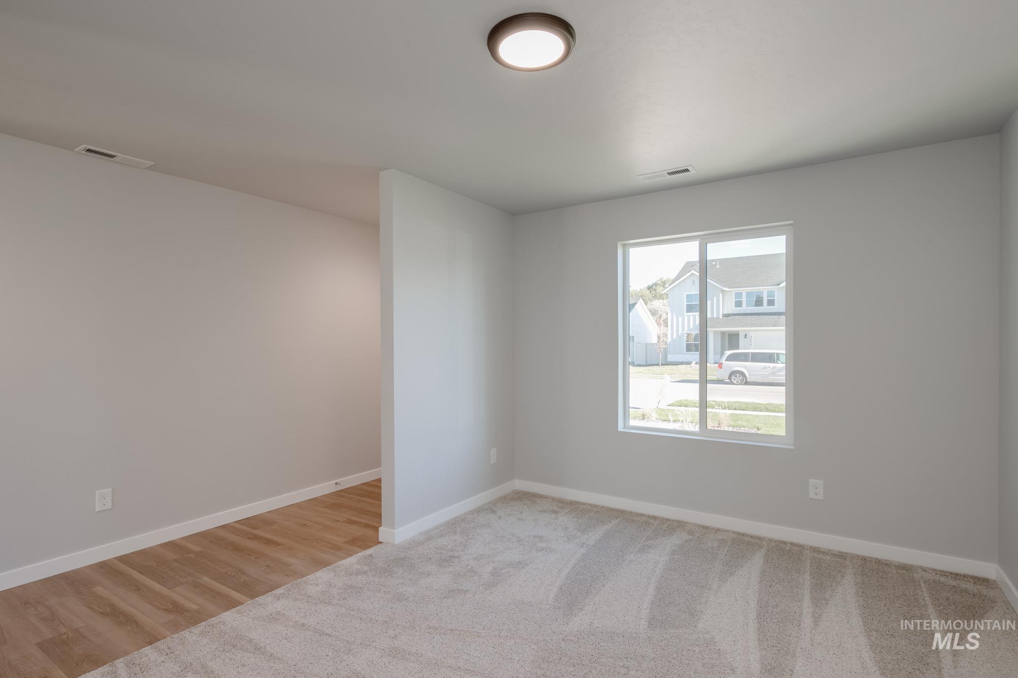 Unfurnished room with light wood-style floors and light colored carpet