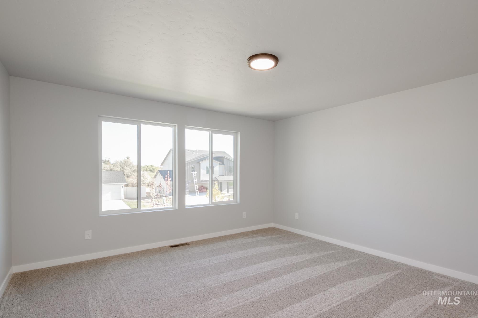 Unfurnished room featuring light carpet and baseboards