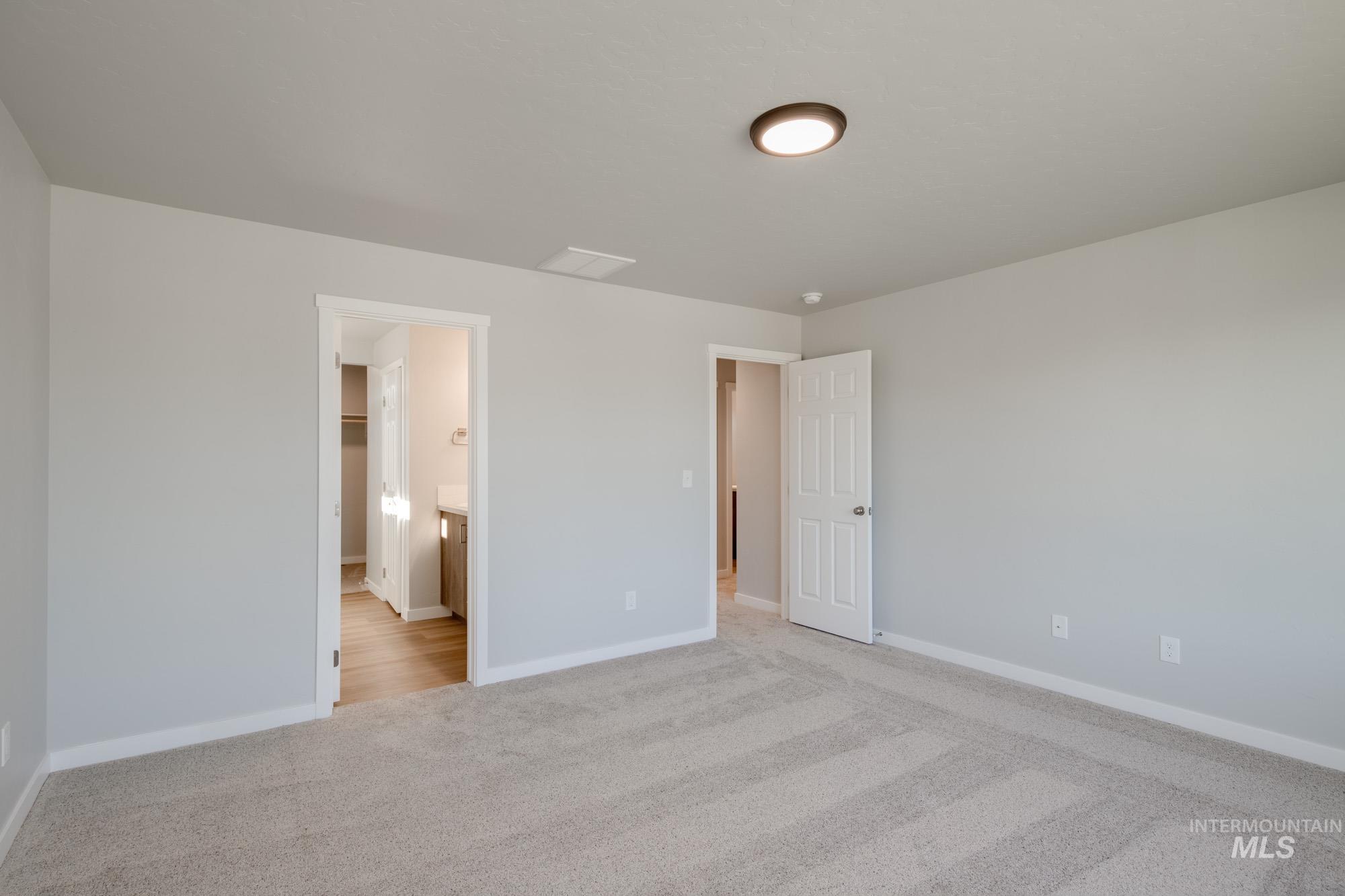 Unfurnished bedroom with light colored carpet and ensuite bathroom