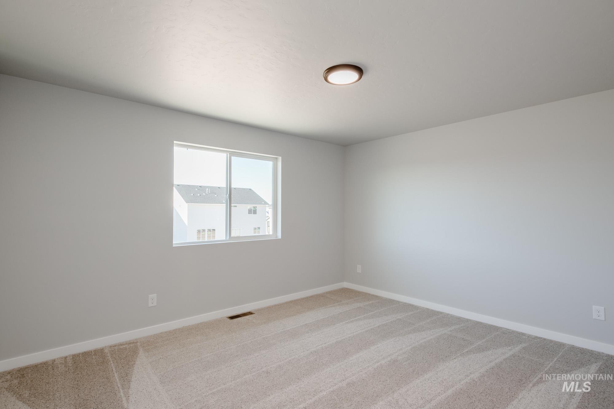 Empty room featuring light colored carpet and baseboards