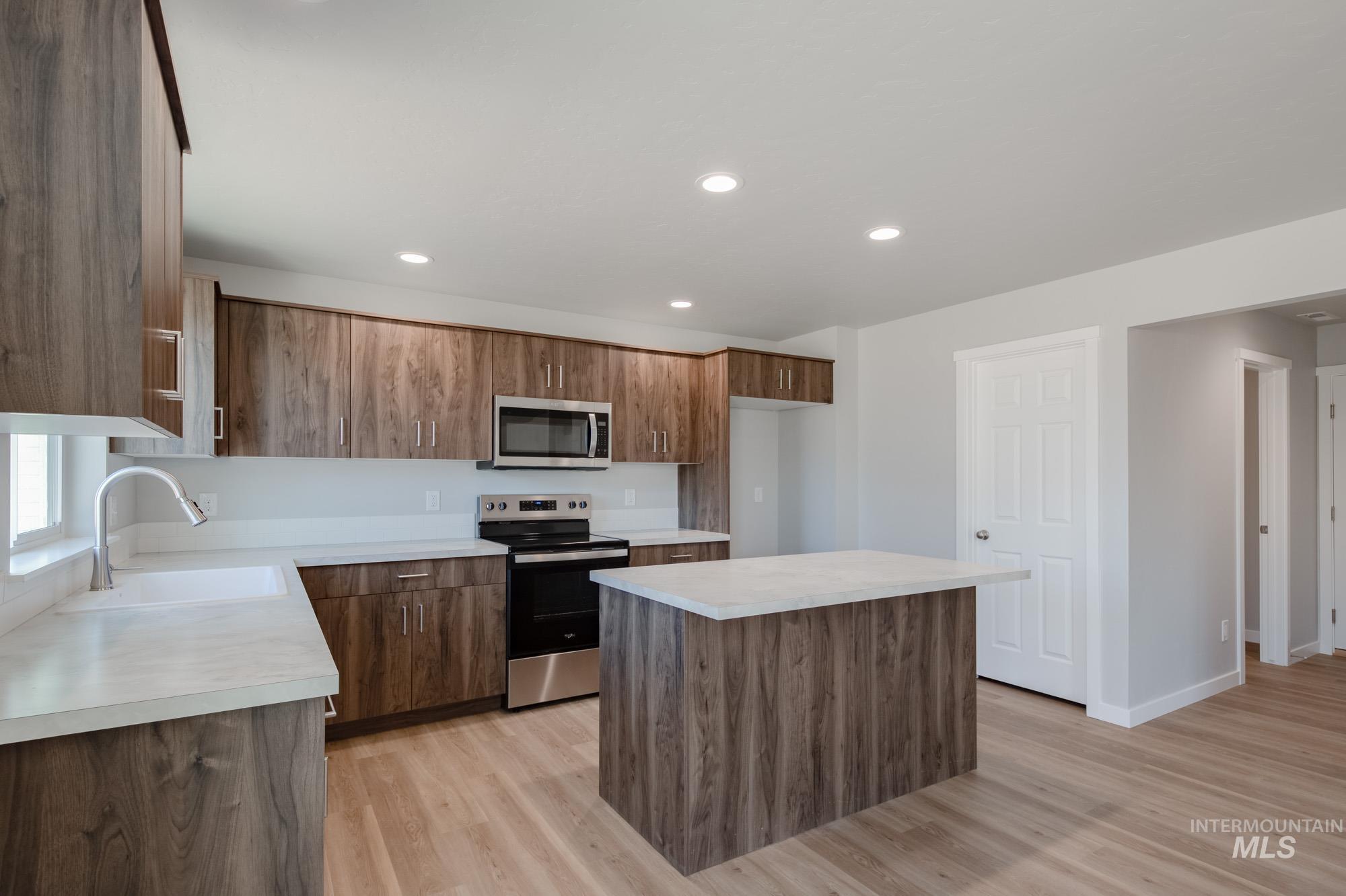 Kitchen with a kitchen island, stainless steel appliances, light wood-style floors, light countertops, and recessed lighting