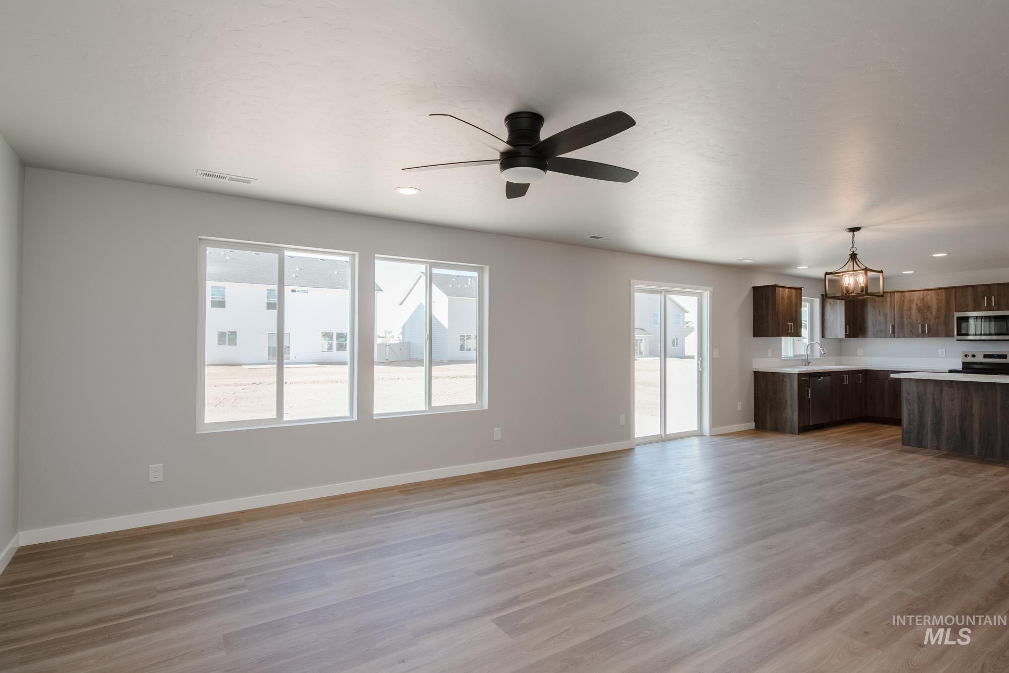 Unfurnished living room featuring light wood finished floors, a ceiling fan, recessed lighting, and a chandelier