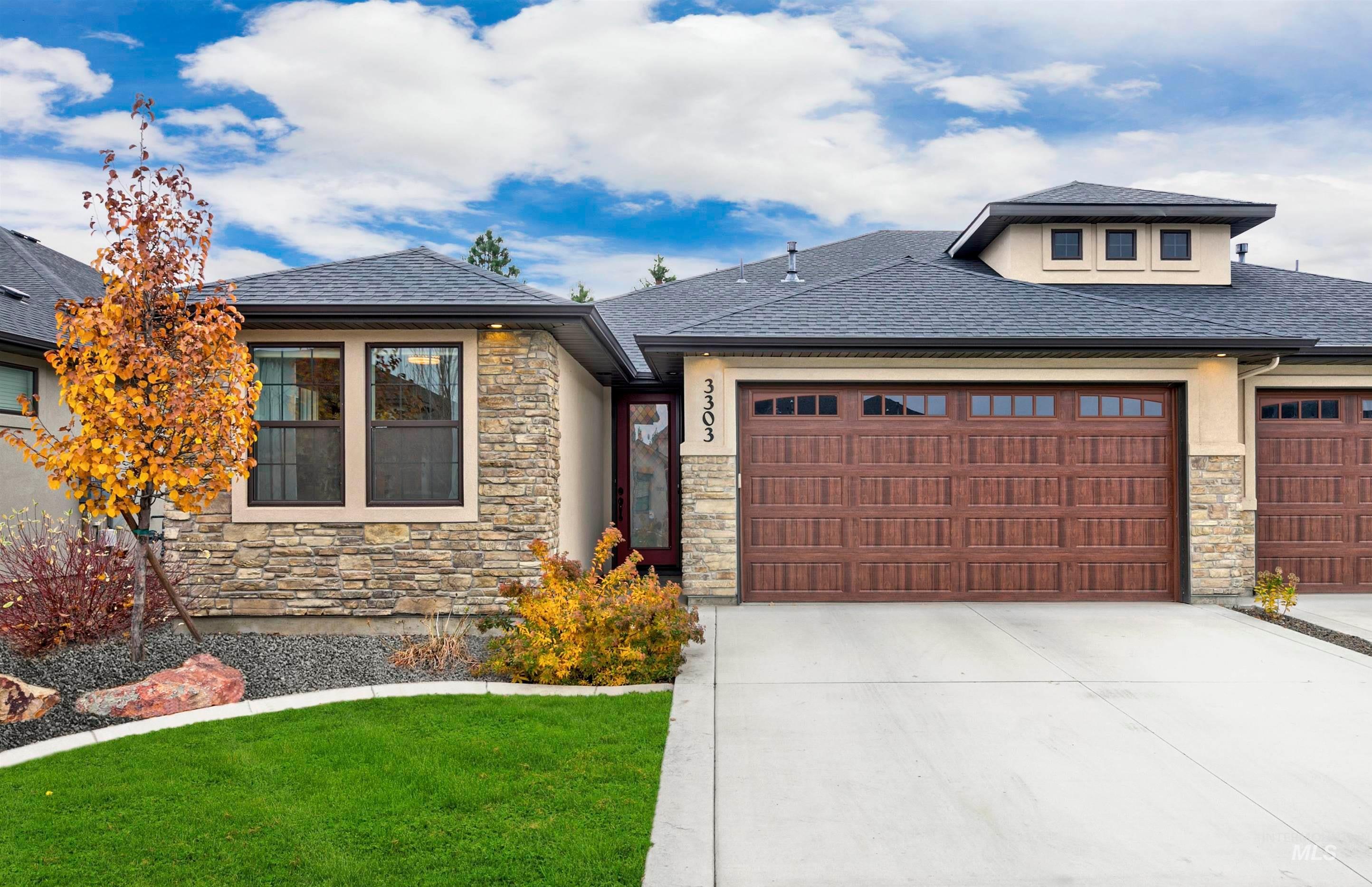 Prairie-style home featuring stone siding, an attached garage, concrete driveway, and a shingled roof
