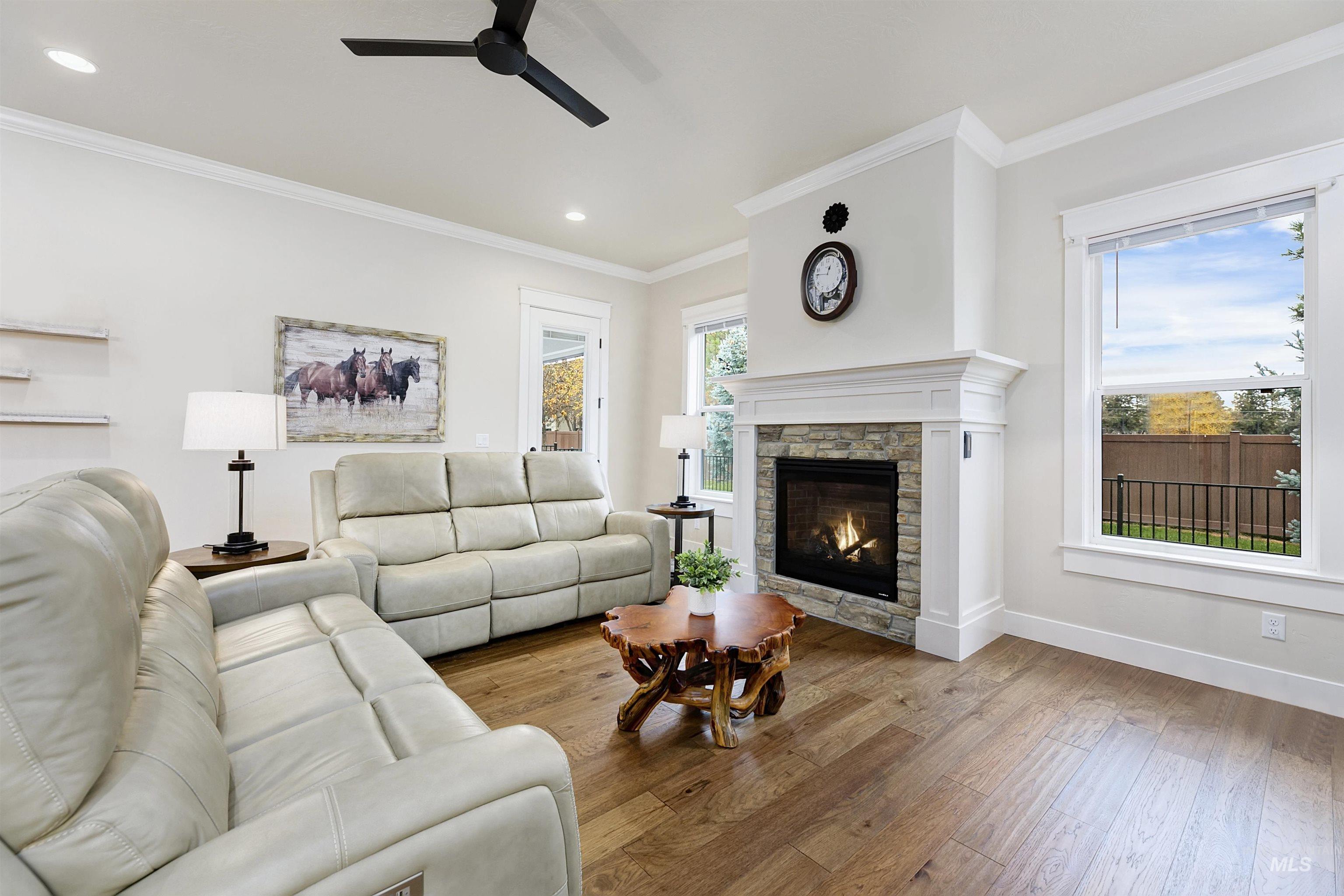 Living room featuring wood-type flooring, ceiling fan, crown molding, a fireplace, and recessed lighting