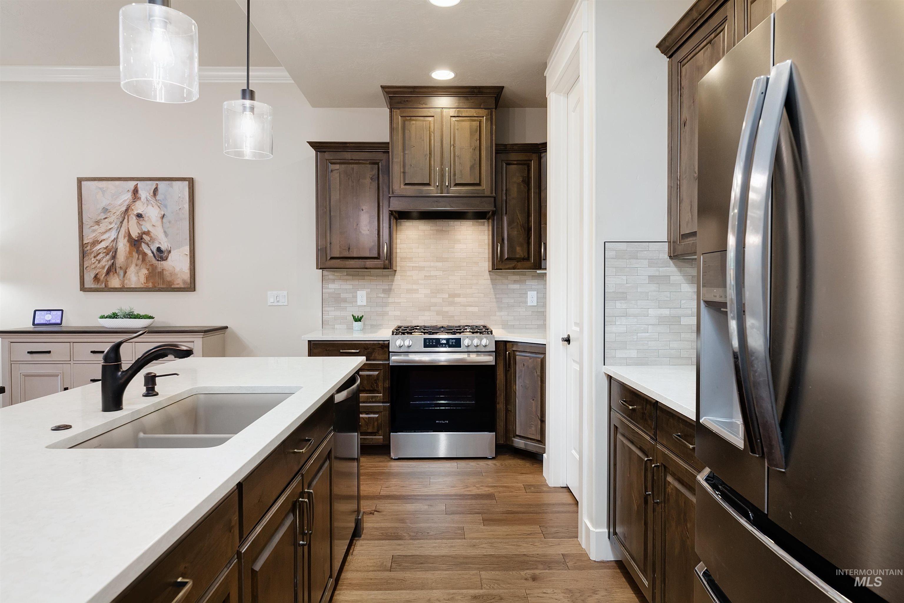 Kitchen featuring appliances with stainless steel finishes, dark brown cabinets, pendant lighting, tasteful backsplash, and recessed lighting