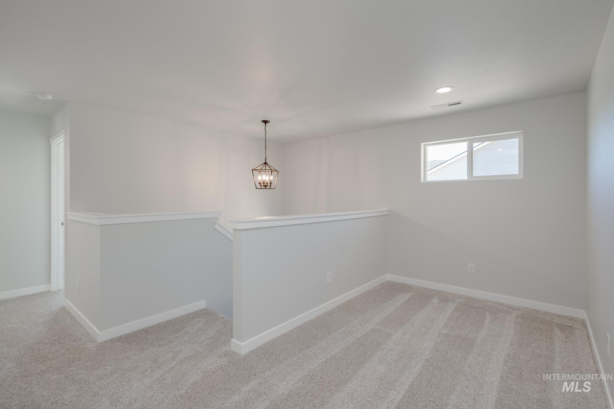 Empty room featuring light carpet, a chandelier, and recessed lighting