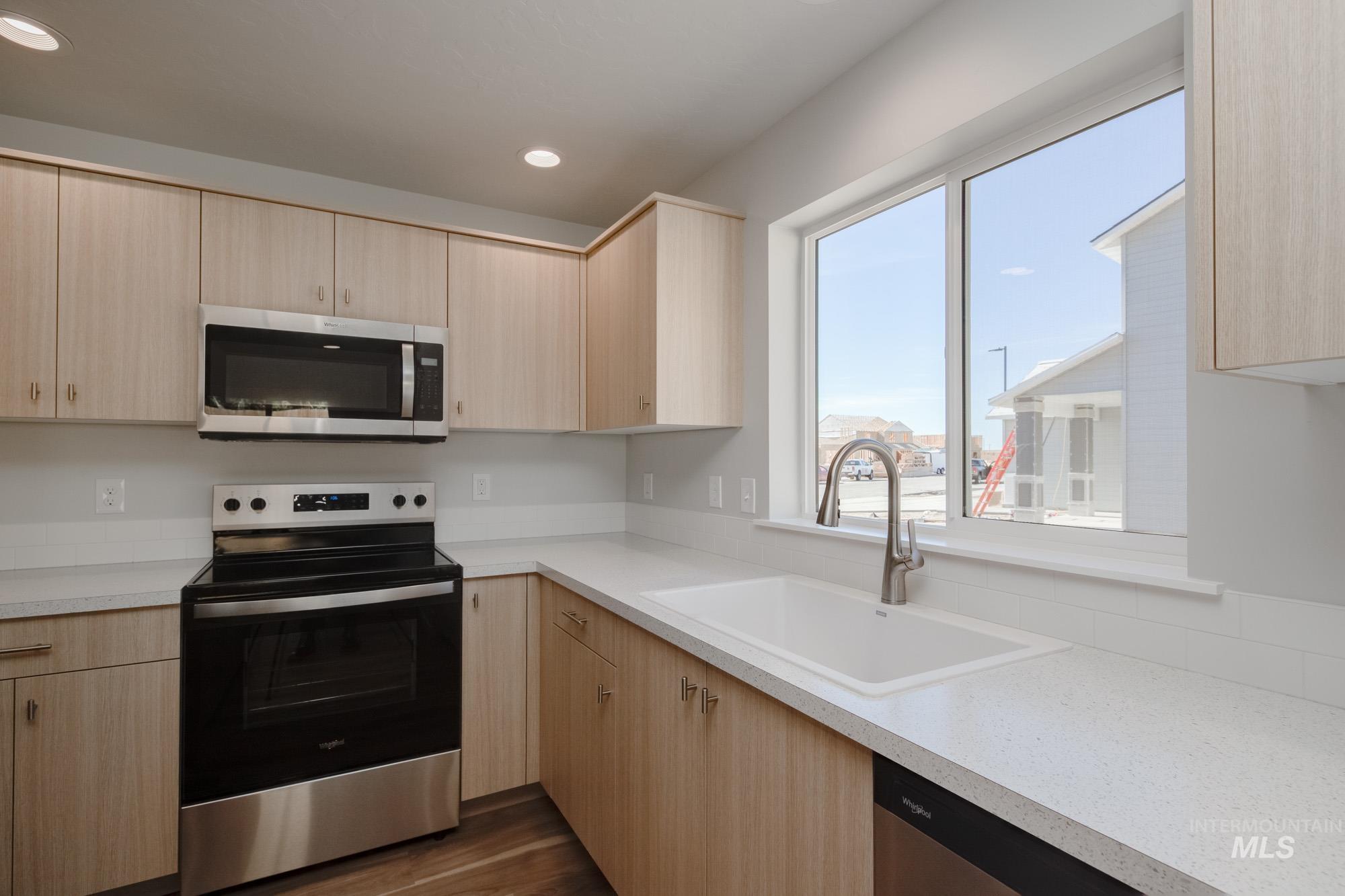 Kitchen featuring light brown cabinets, stainless steel appliances, light countertops, and recessed lighting