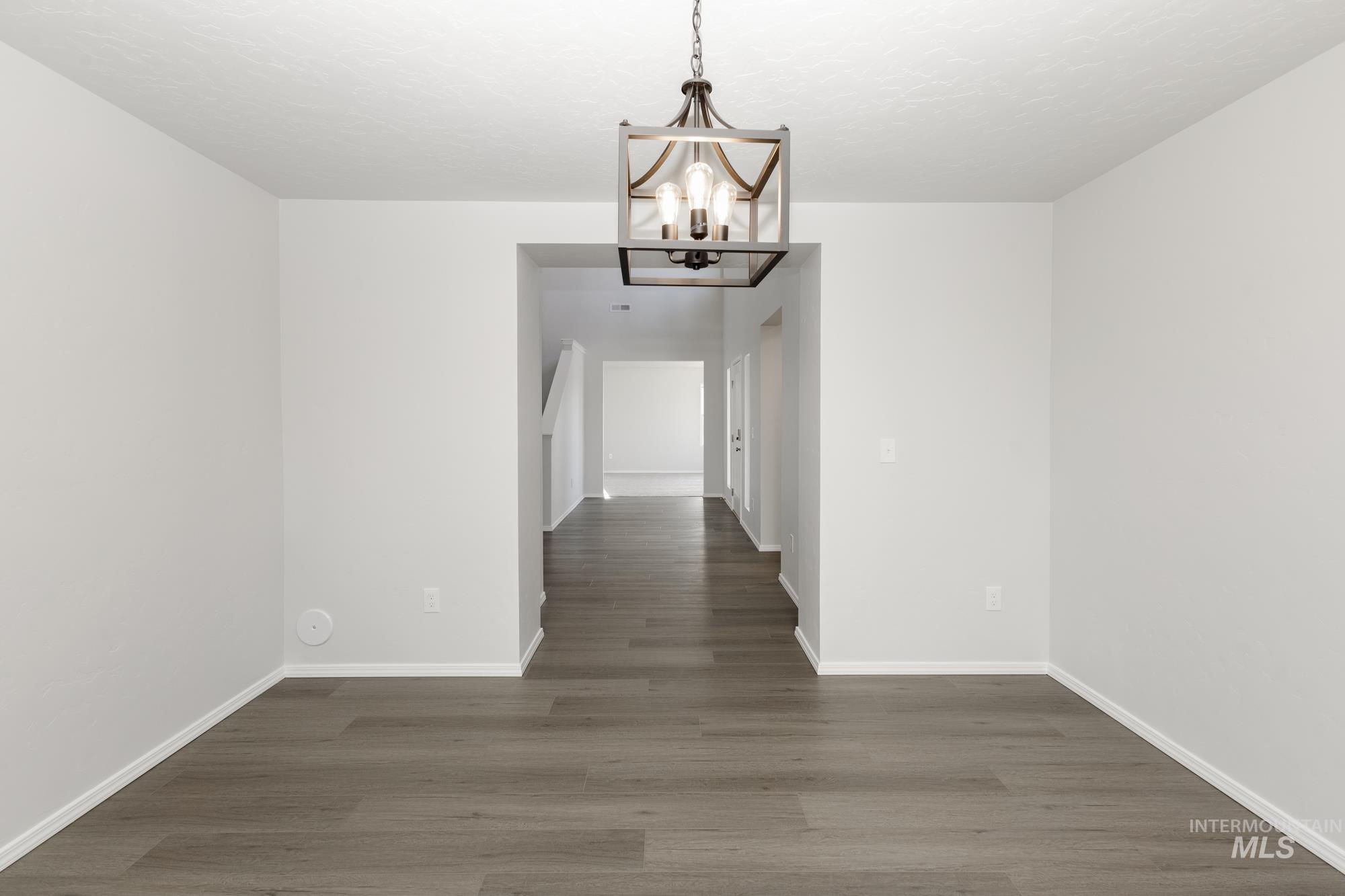 Unfurnished dining area featuring a chandelier and dark wood finished floors