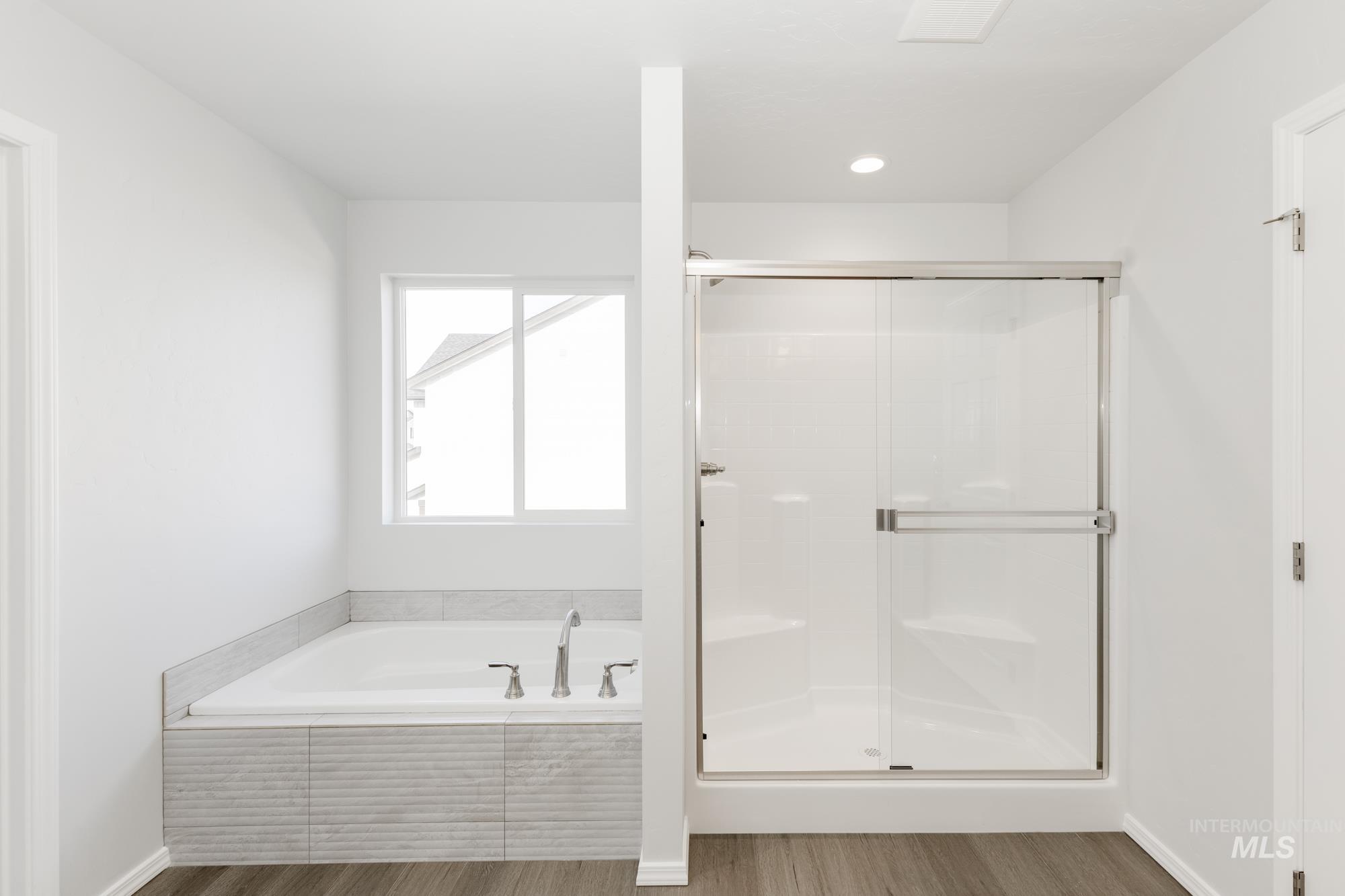 Bathroom featuring a garden tub, a shower stall, and wood finished floors