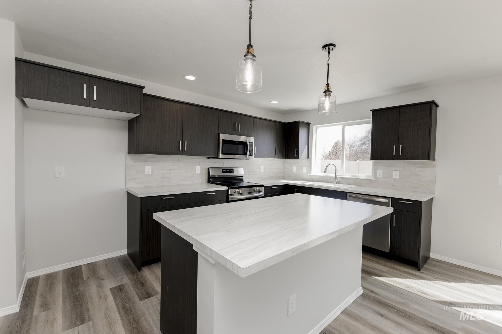 Kitchen with light countertops, decorative backsplash, hanging light fixtures, appliances with stainless steel finishes, and recessed lighting