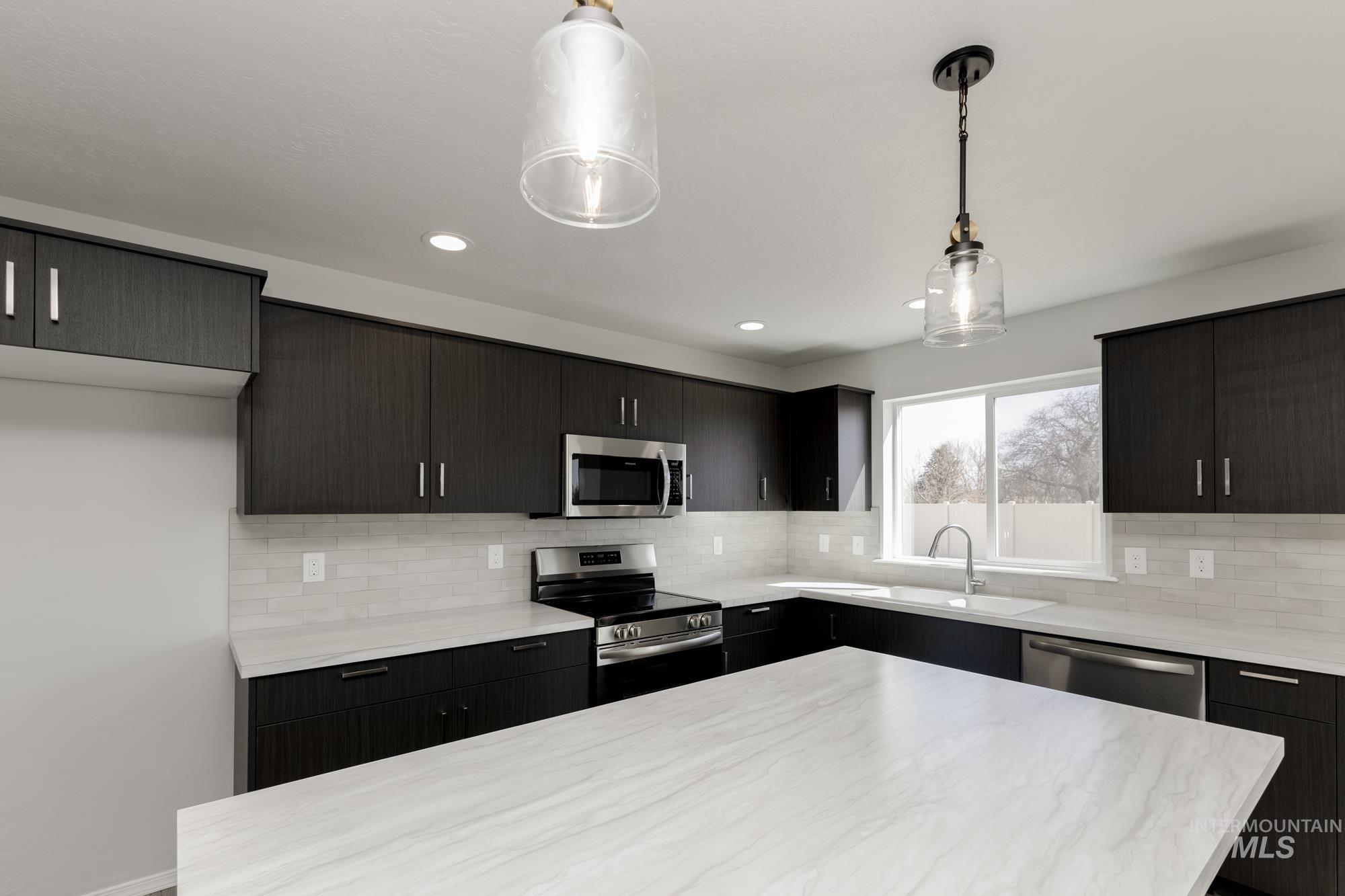 Kitchen with appliances with stainless steel finishes, hanging light fixtures, backsplash, a kitchen island, and modern cabinets