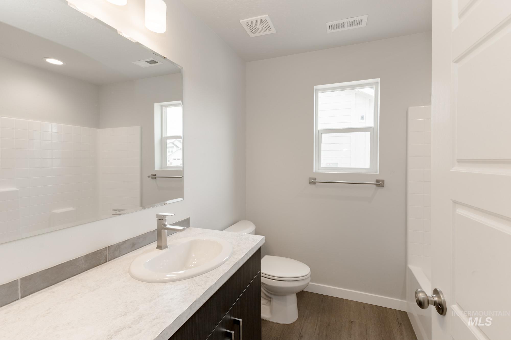 Full bath featuring vanity and dark wood-type flooring