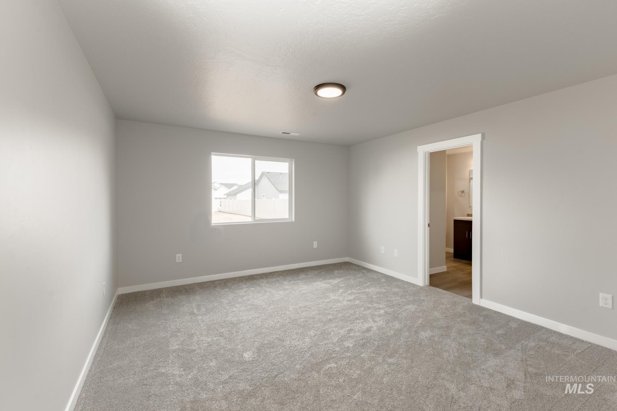Empty room featuring light colored carpet and baseboards