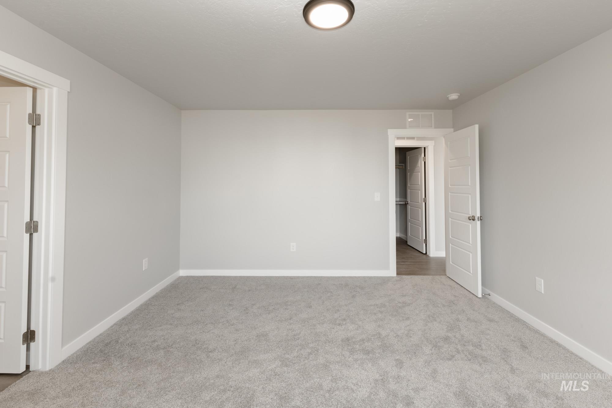 Empty room featuring baseboards and light carpet