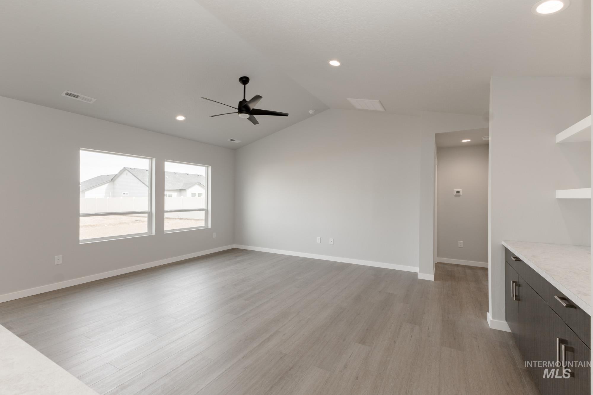 Unfurnished living room with lofted ceiling, light wood finished floors, recessed lighting, and a ceiling fan