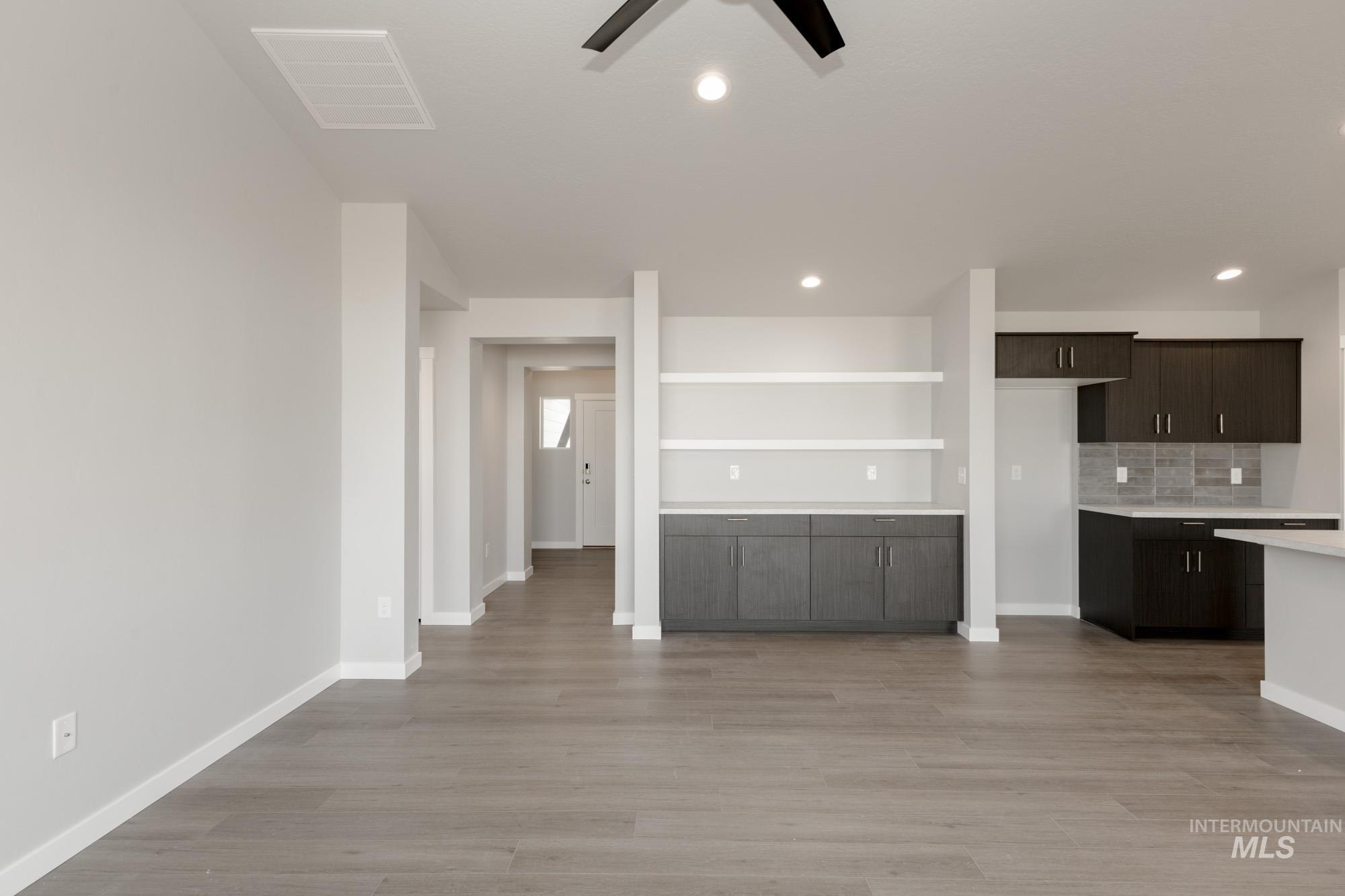 Kitchen with backsplash, dark brown cabinets, light wood finished floors, recessed lighting, and open floor plan