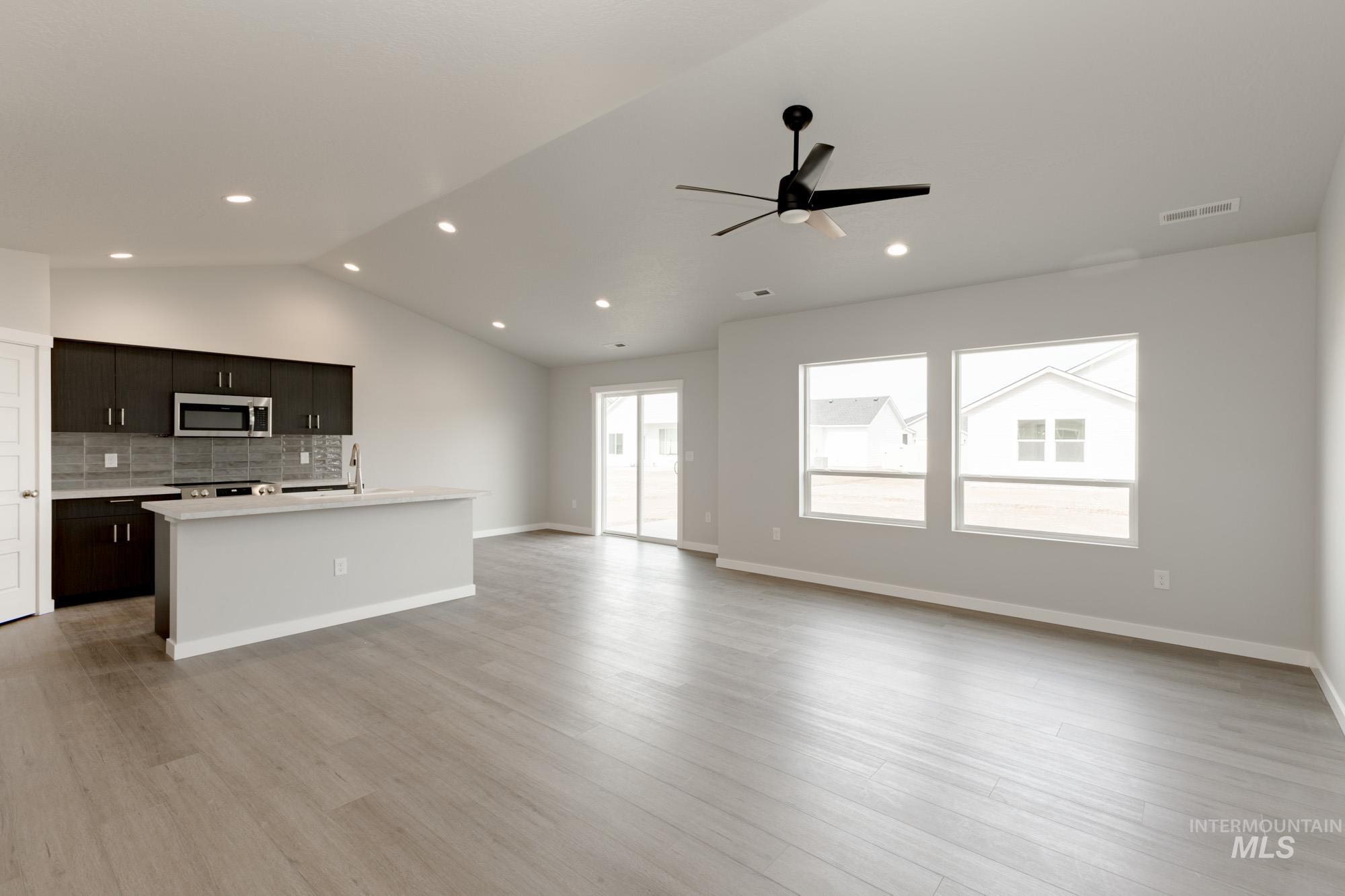 Unfurnished living room with lofted ceiling, light wood-type flooring, ceiling fan, and recessed lighting