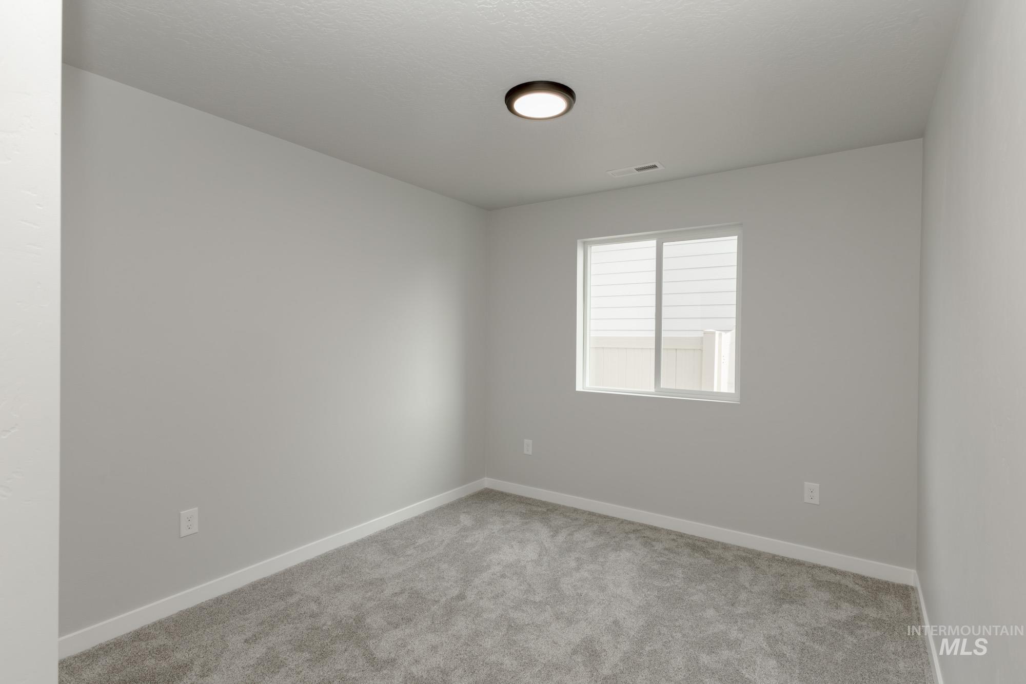 Spare room featuring carpet flooring and baseboards