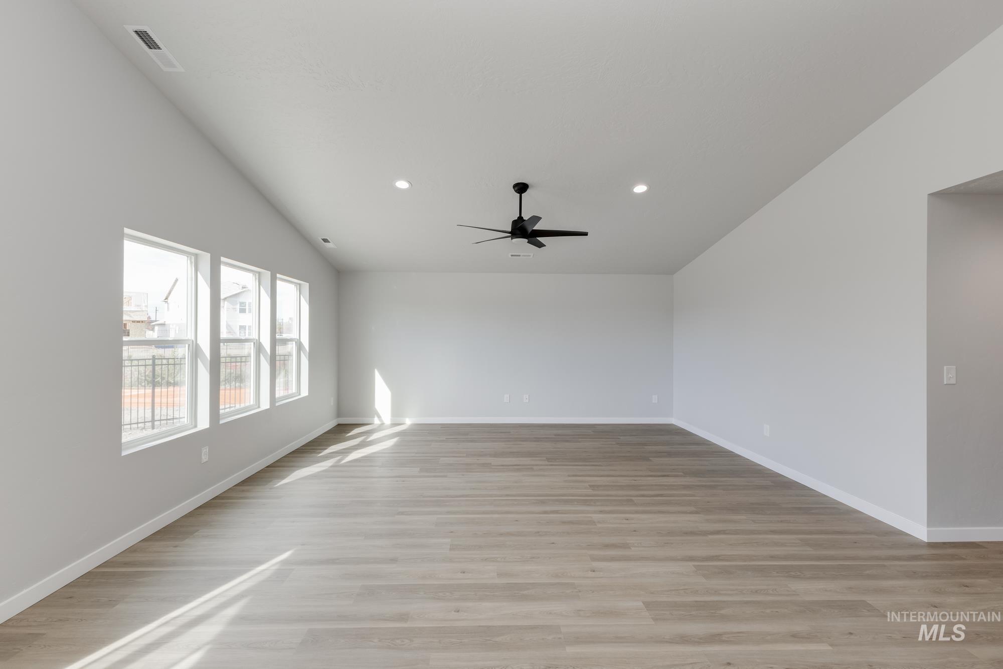 Spare room featuring light wood finished floors, vaulted ceiling, recessed lighting, and a ceiling fan