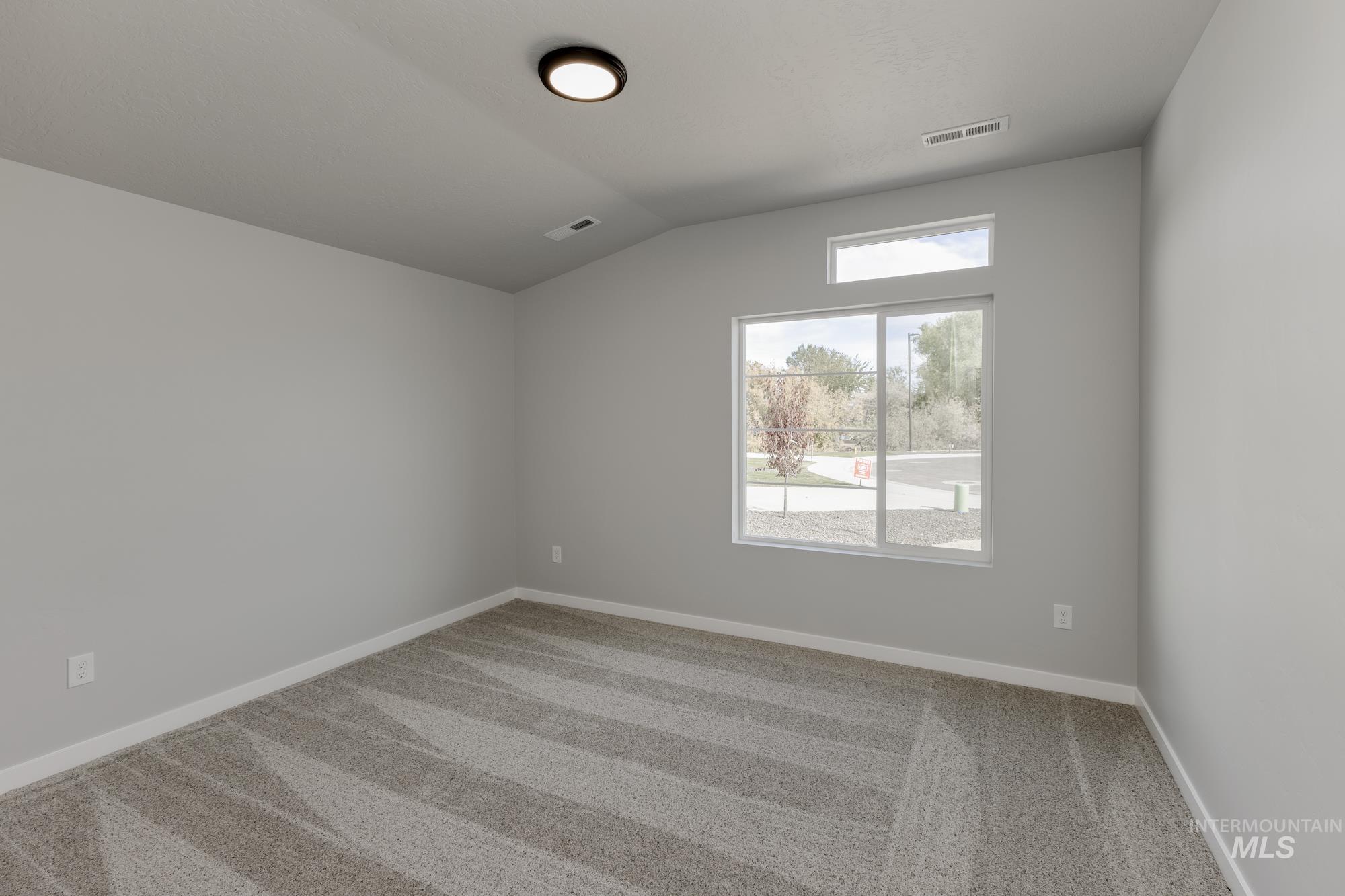 Unfurnished room with light carpet and vaulted ceiling