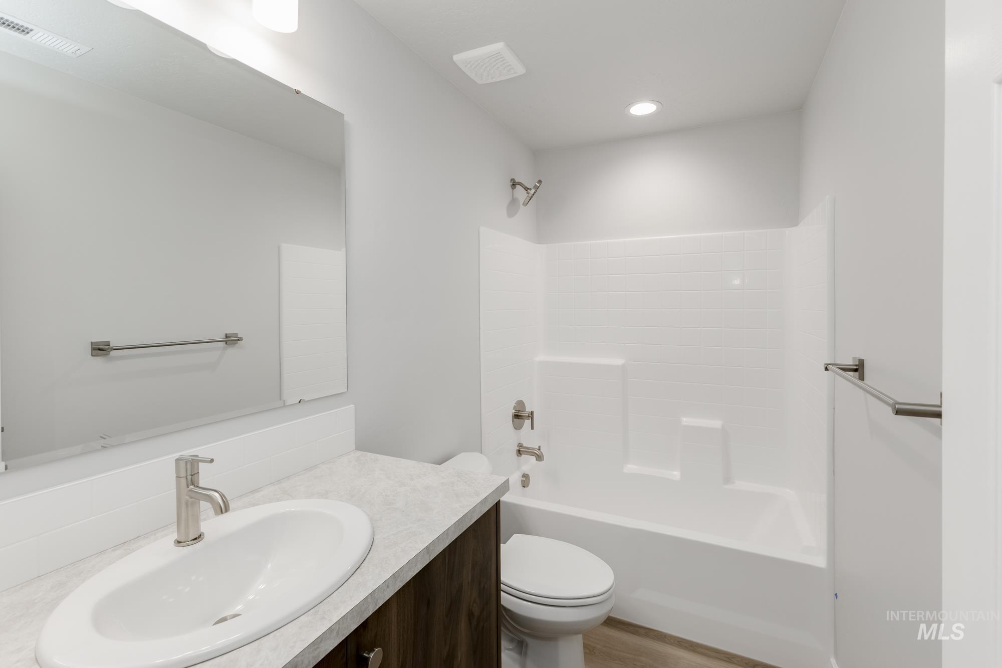 Full bath with vanity, washtub / shower combination, and light wood finished floors