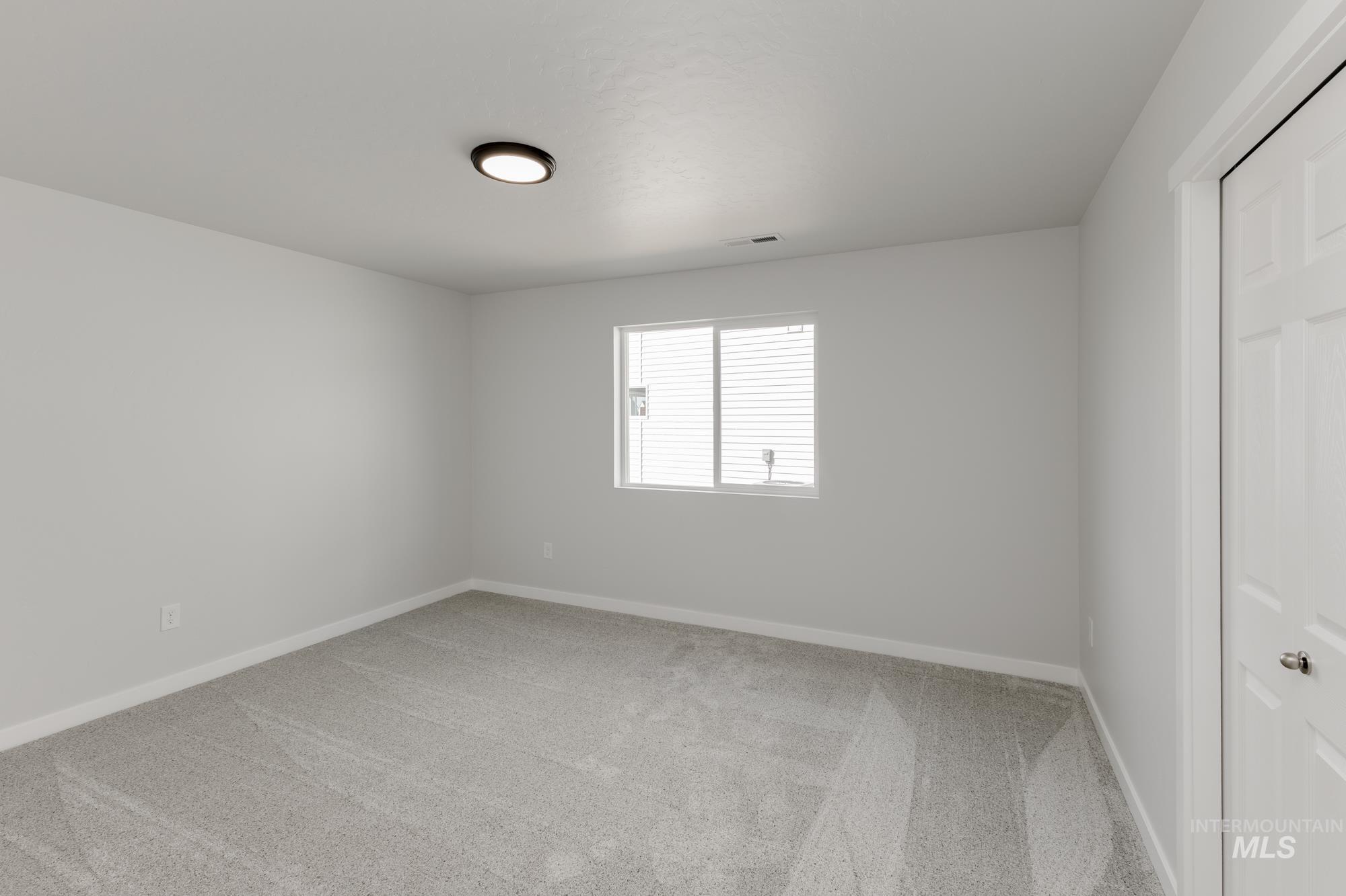 Spare room featuring light carpet and baseboards