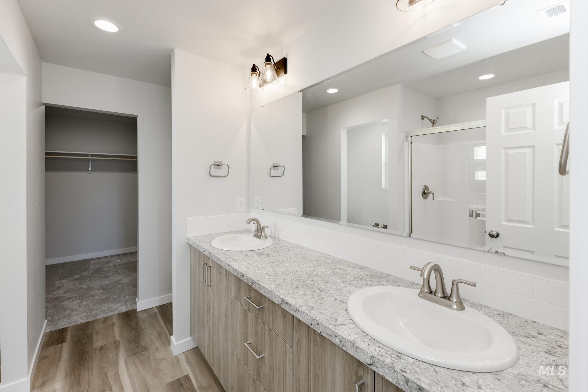 Bathroom with recessed lighting, a shower stall, double vanity, light wood-style flooring, and a spacious closet