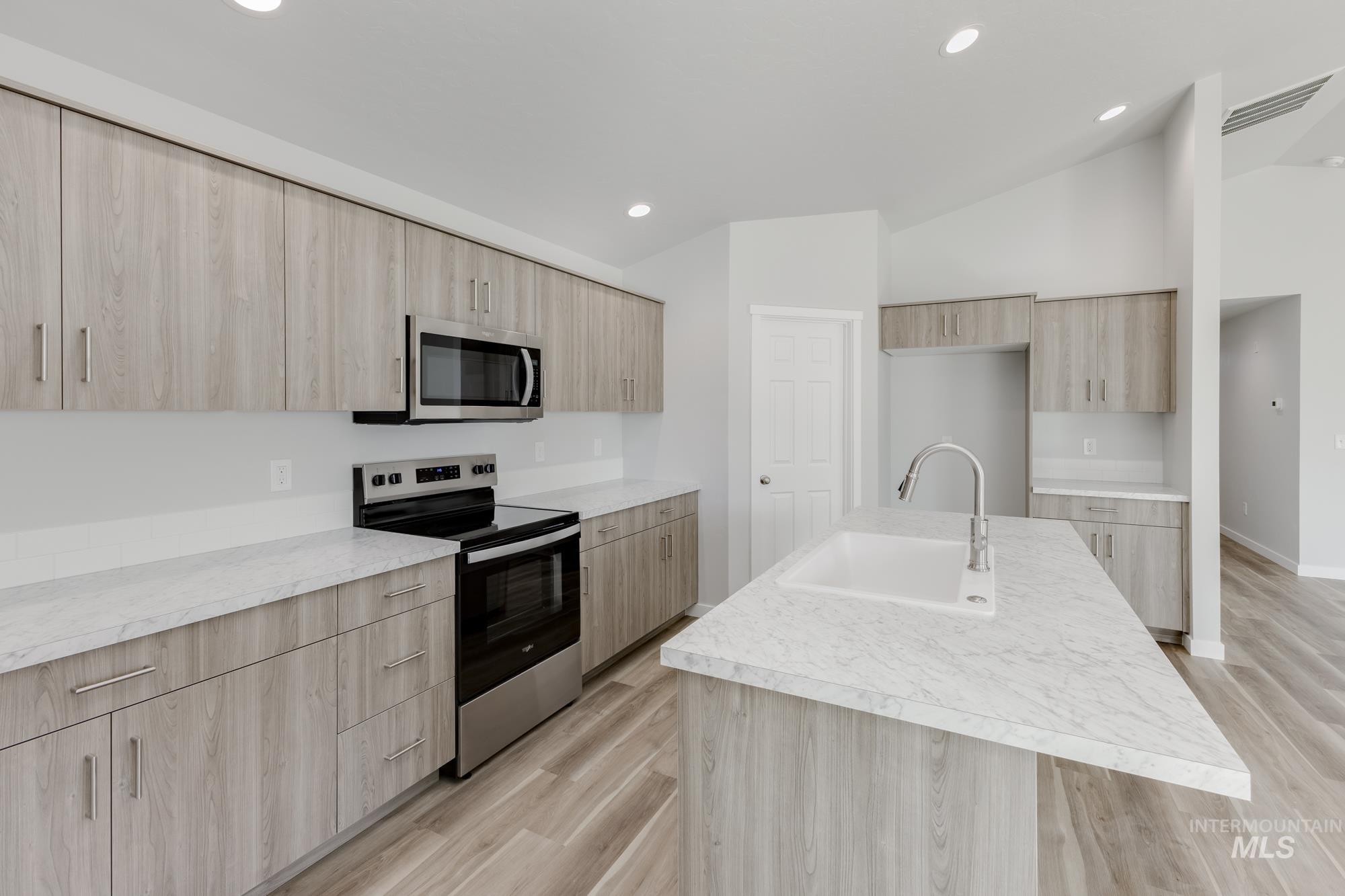 Kitchen featuring light brown cabinetry, appliances with stainless steel finishes, light wood-style floors, modern cabinets, and recessed lighting