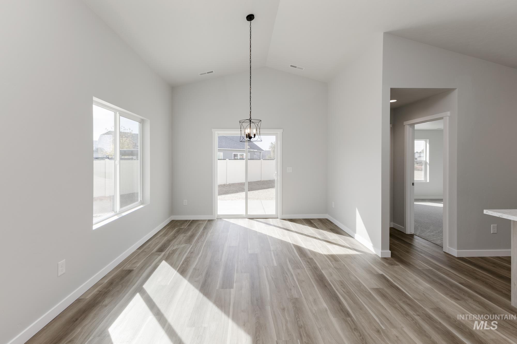 Unfurnished dining area with lofted ceiling, light wood-style flooring, and a chandelier