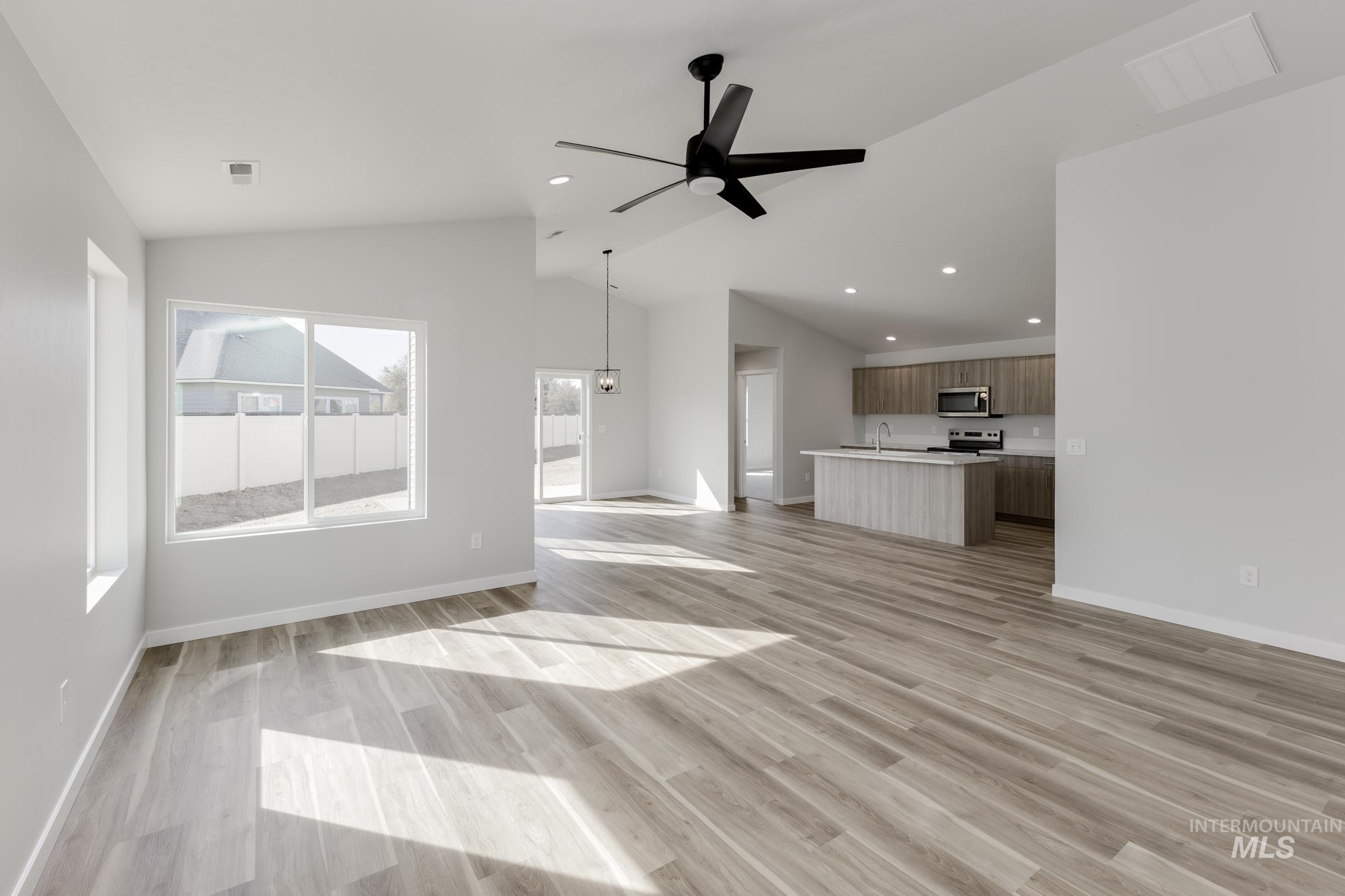 Unfurnished living room featuring light wood finished floors, ceiling fan, lofted ceiling, and recessed lighting