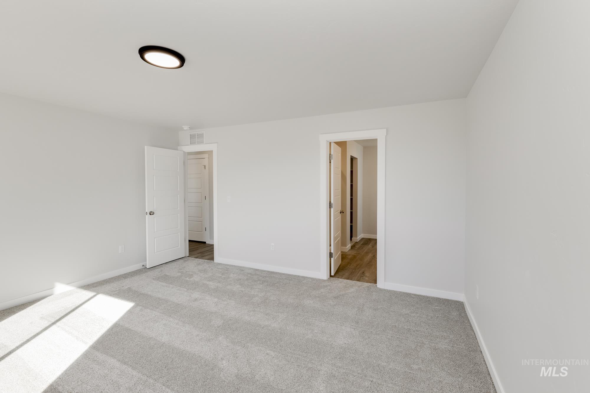 Unfurnished bedroom with light carpet and baseboards