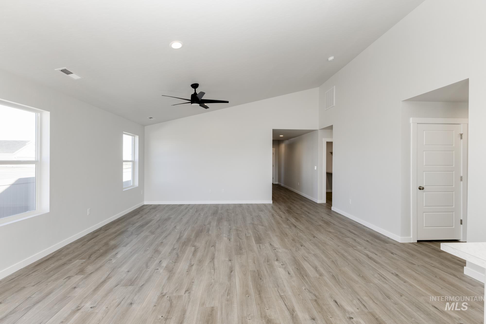 Empty room with light wood-type flooring, a ceiling fan, high vaulted ceiling, and recessed lighting