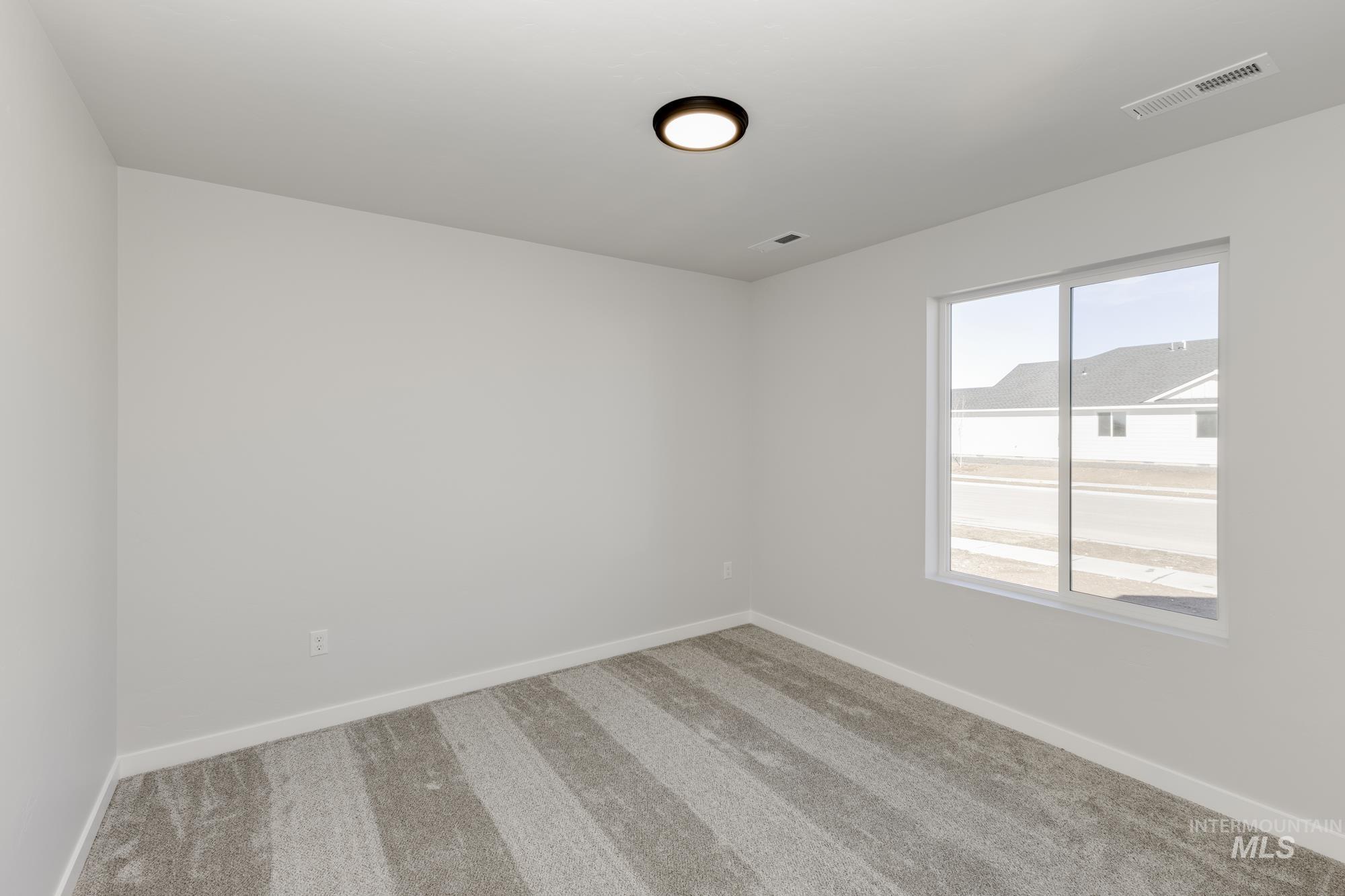 Carpeted spare room featuring baseboards